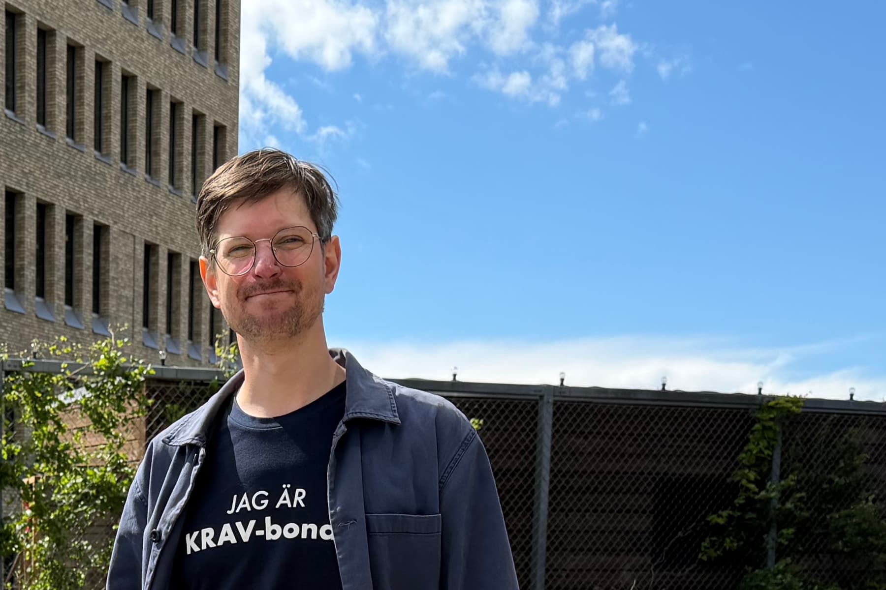 Två personer som står på en träbro framför en byggnad.