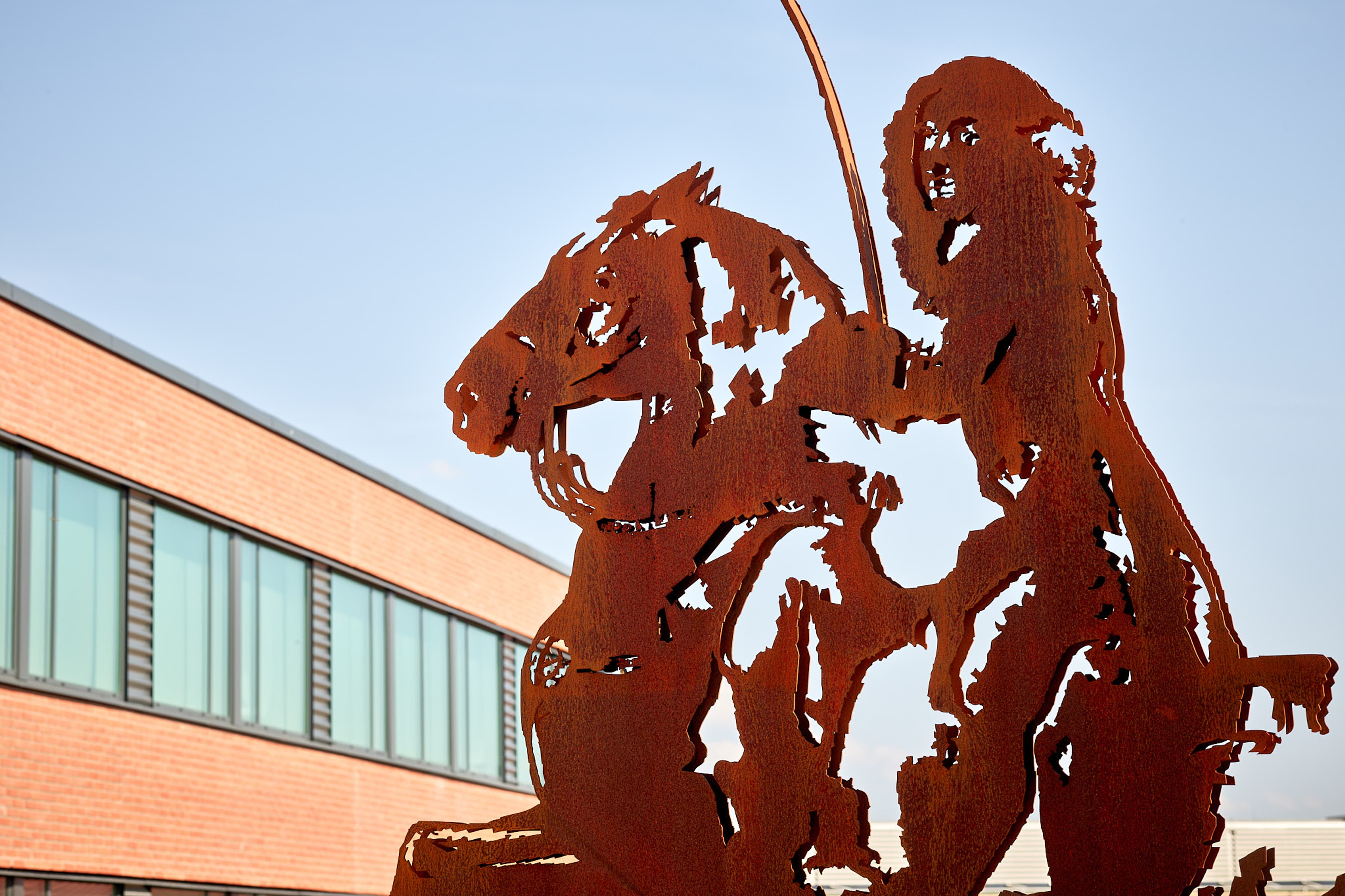 En staty av en man som rider på en häst framför en byggnad.