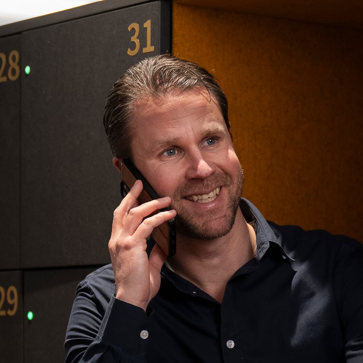 En man som sitter i ett bås och pratar i mobiltelefonen.