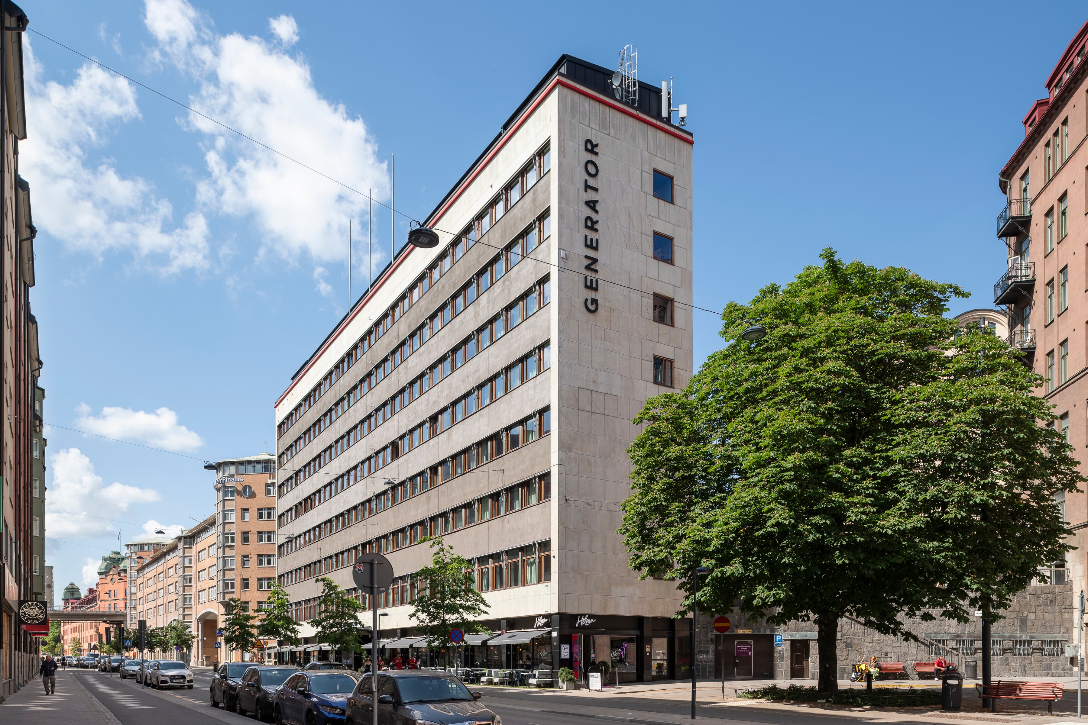 En stadsgata kantad av parkerade bilar och höga byggnader.