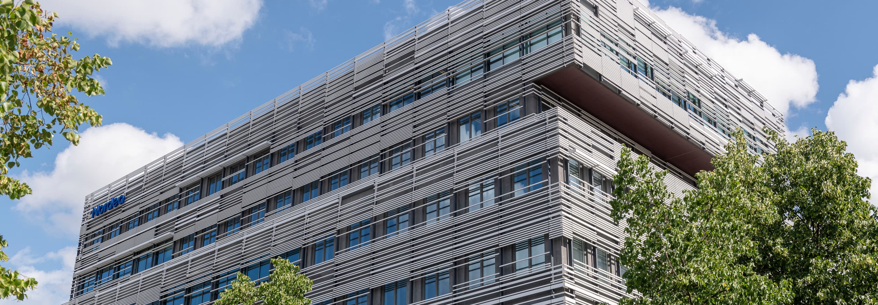 En hög byggnad med många fönster intill träd.