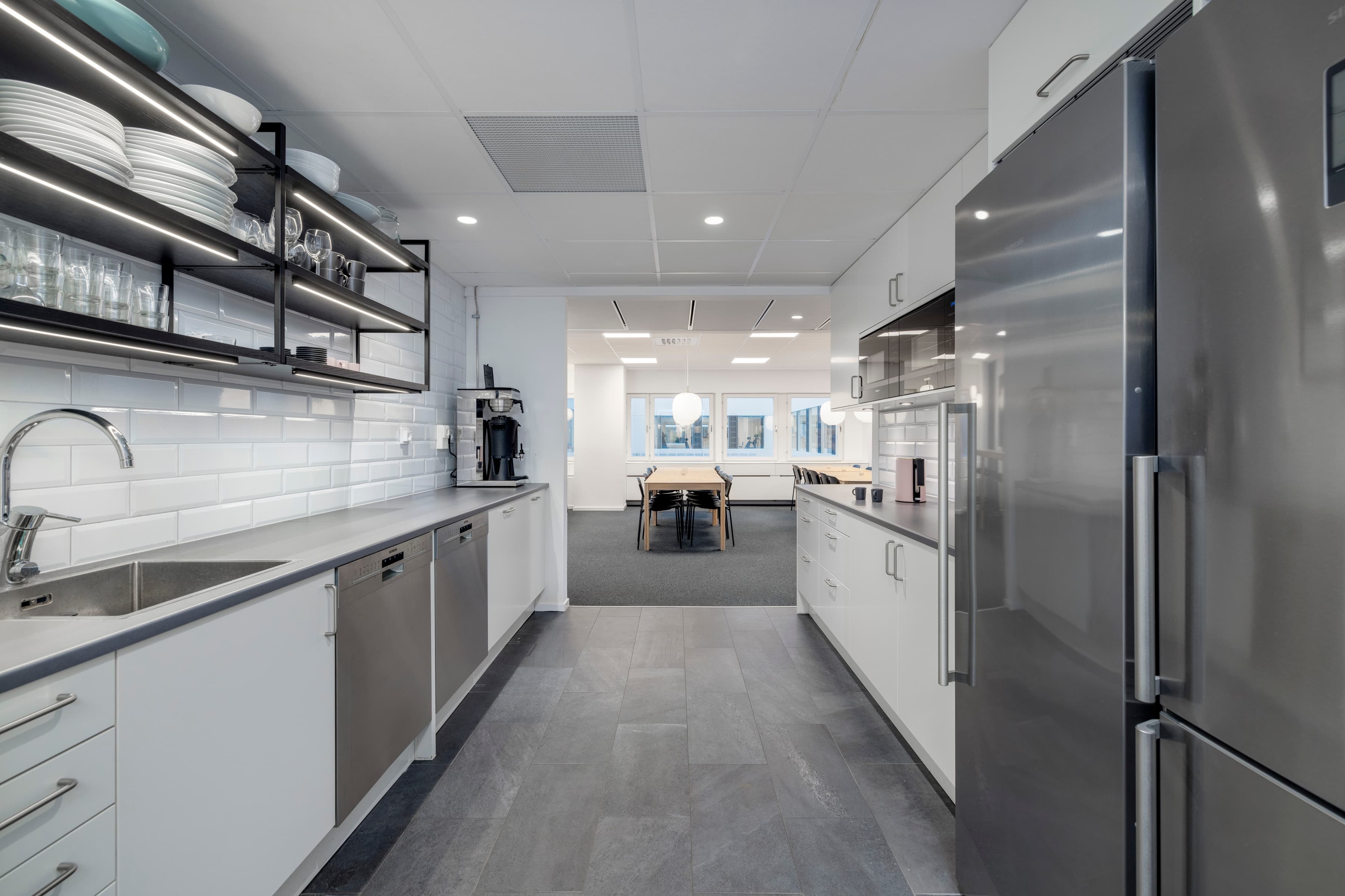 Ett kök med vitvaror i rostfritt stål och vita skåp.