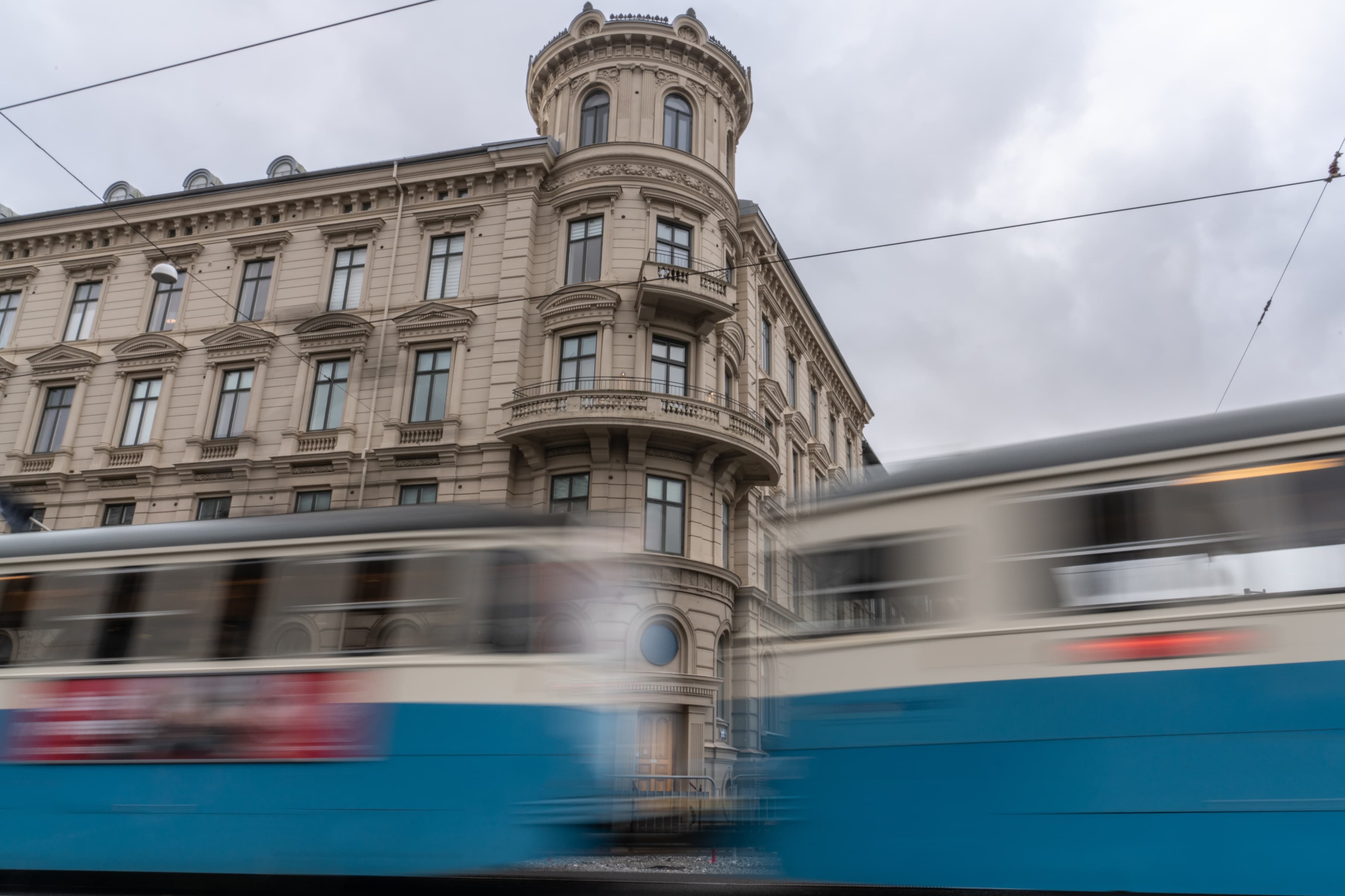 Ett suddigt foto av ett tåg som passerar förbi en byggnad.