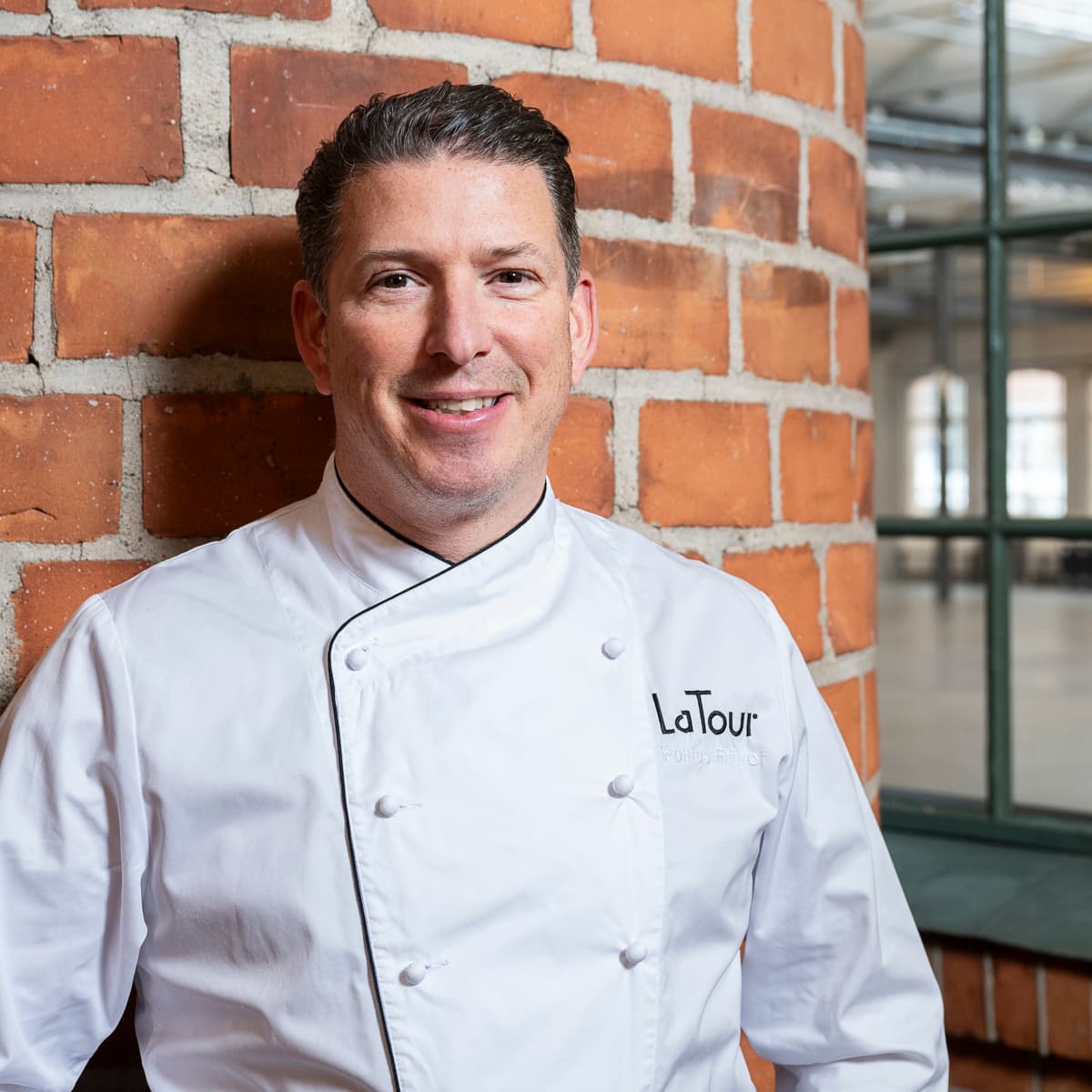 En man som står framför en tegelvägg.