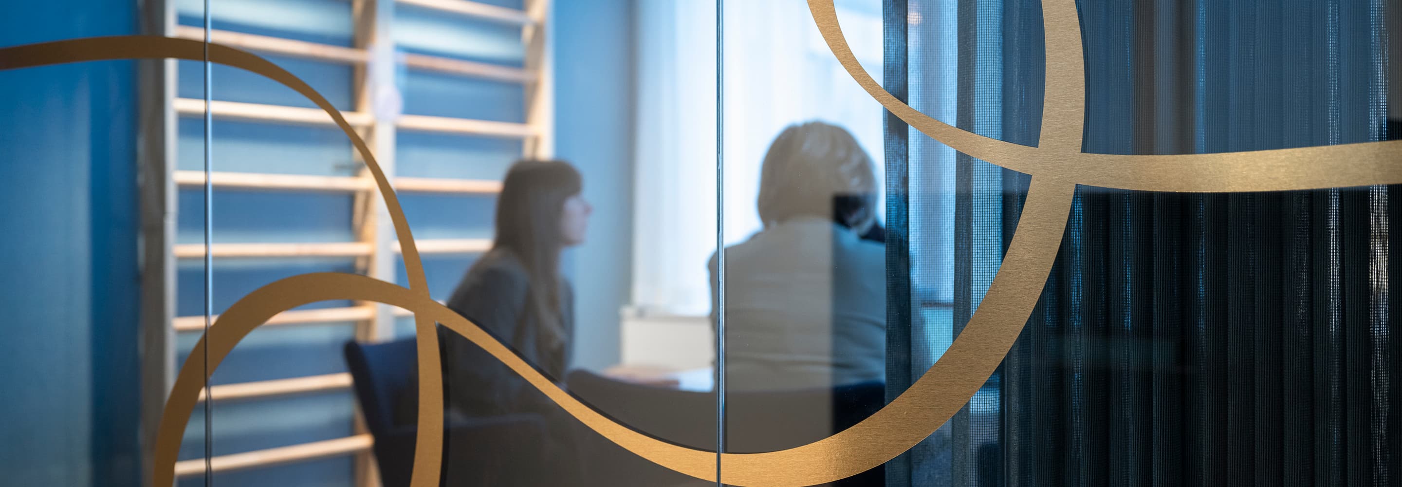 En kvinna sitter vid ett skrivbord framför en glasvägg.