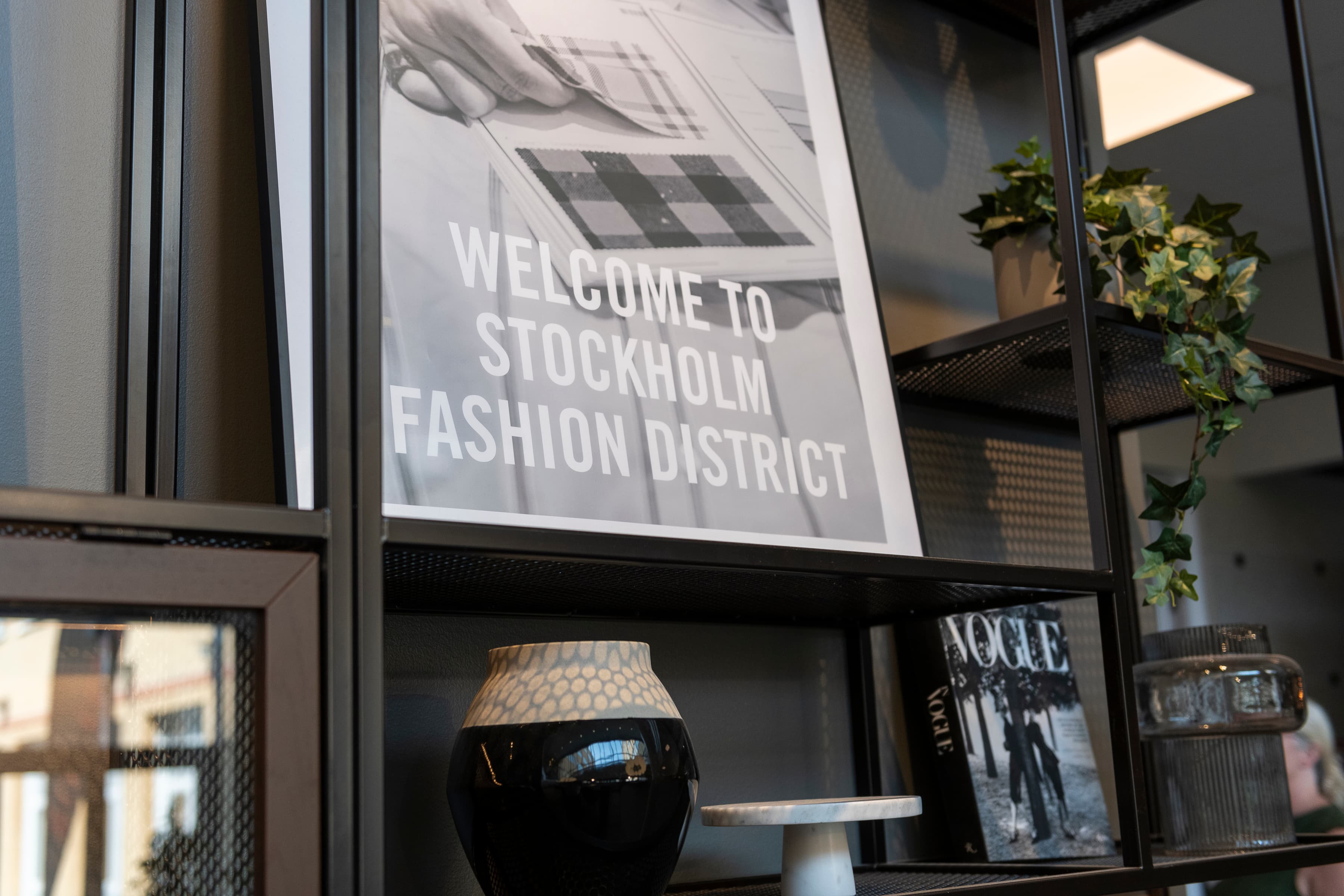 En svart vas som står på en trähylla.