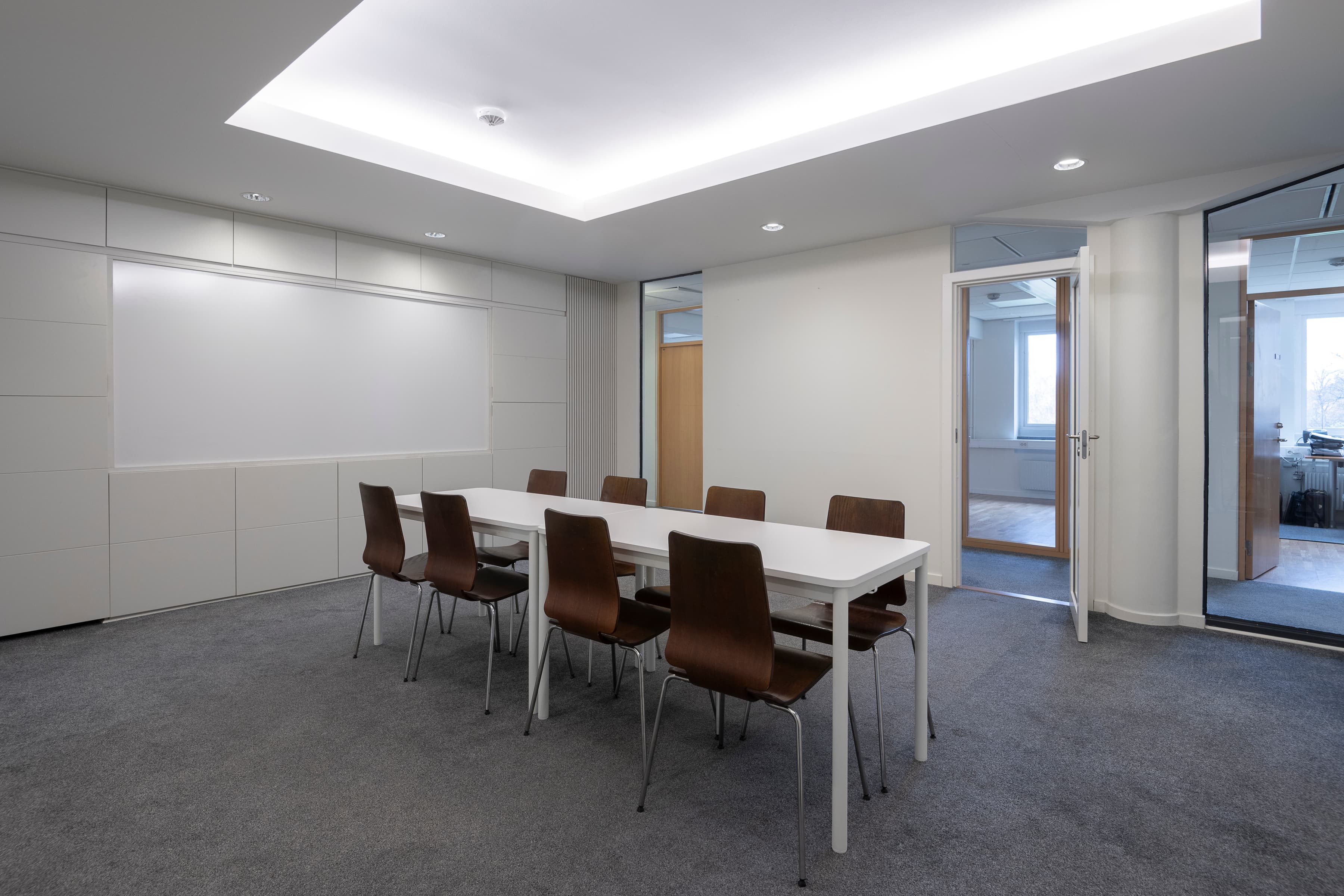 Ett konferensrum med ett vitt bord och bruna stolar.