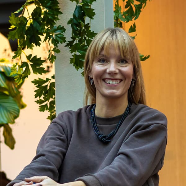 En kvinna som sitter i en stol och ler mot kameran.