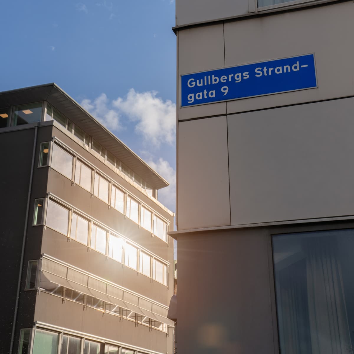 En hög byggnad med en blå gatuskylt på sidan.