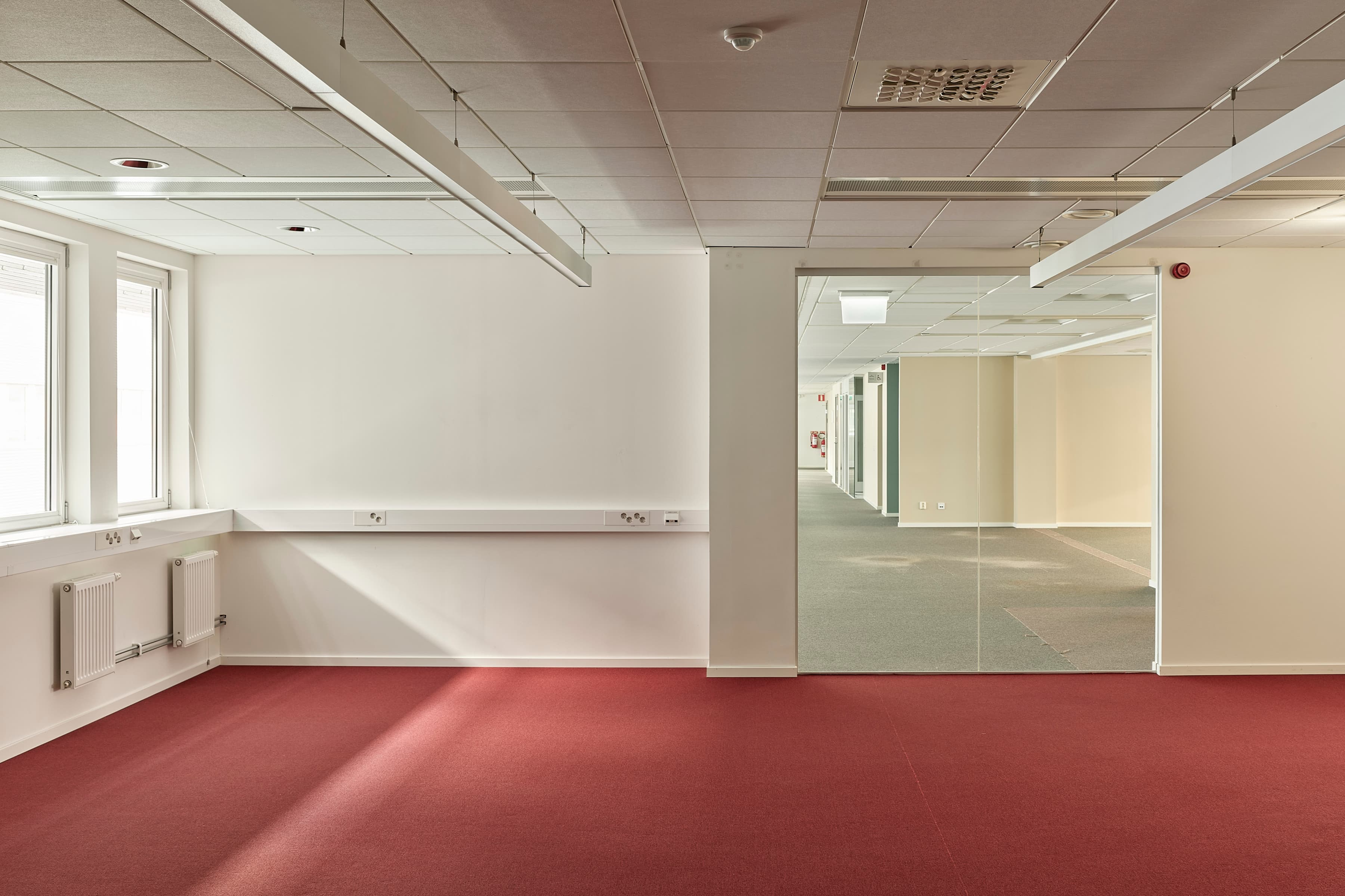 Ett tomt rum med en röd matta och en vit vägg.