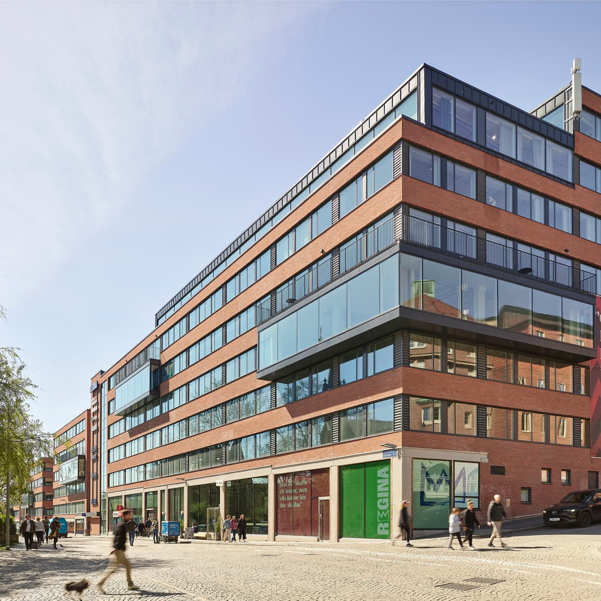 En grupp människor som går längs en gata bredvid en hög byggnad.