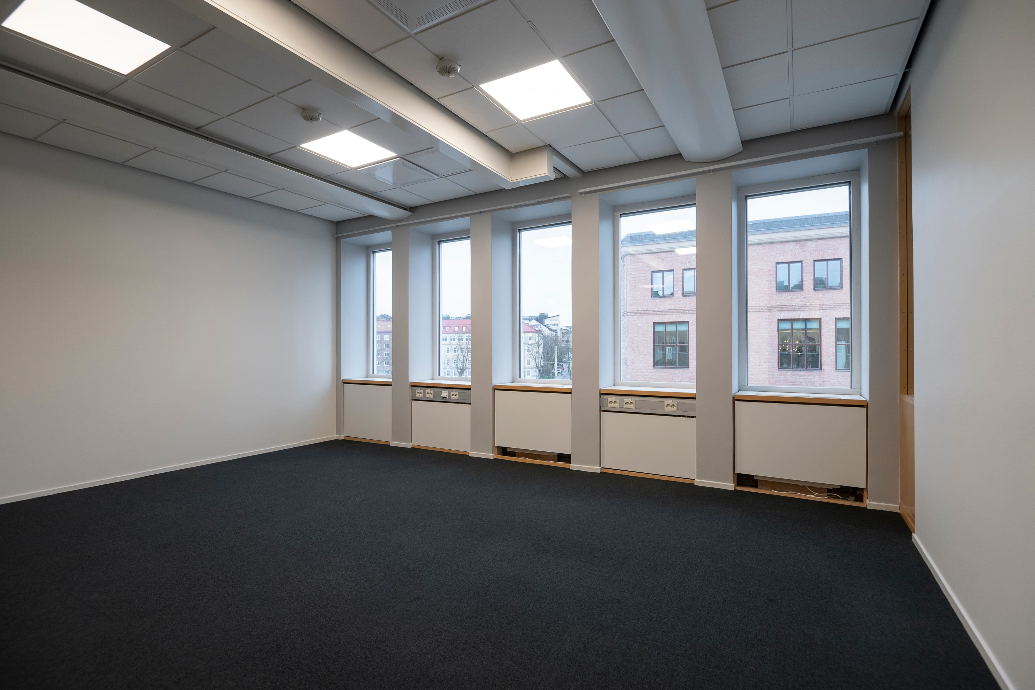 Ett tomt rum med tre fönster och en svart matta.