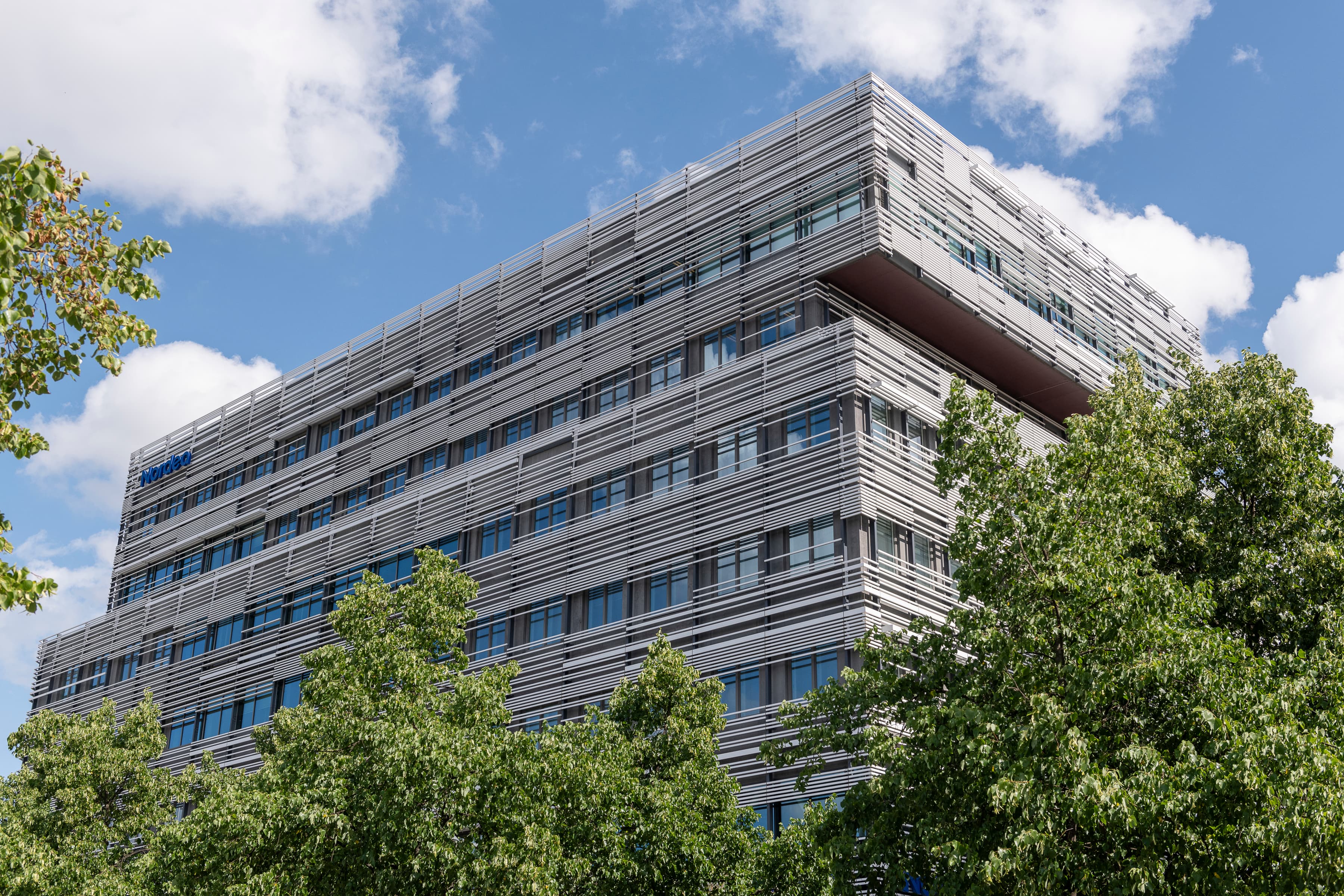 En hög byggnad med många fönster intill träd.