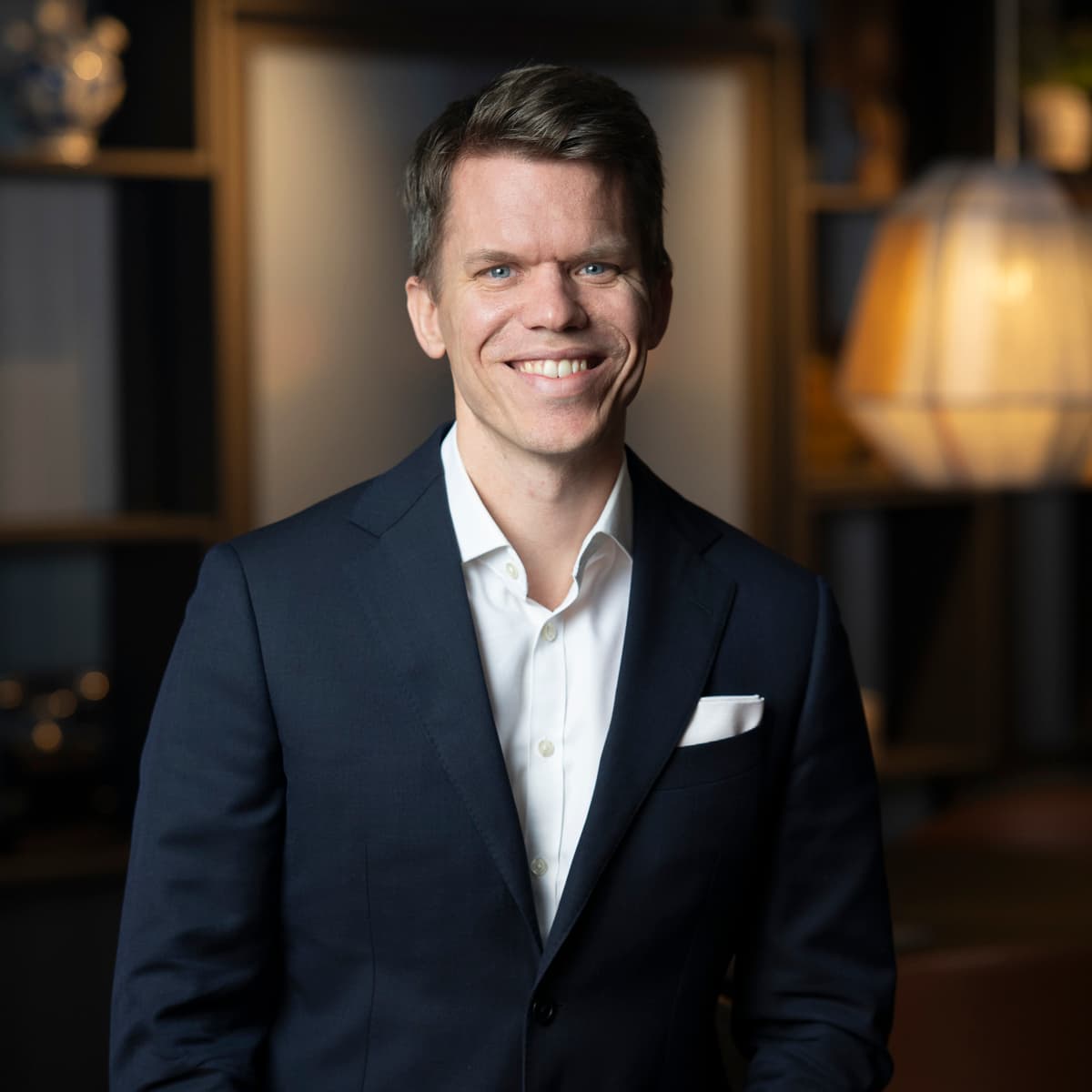 En man i kostym som ler mot kameran.