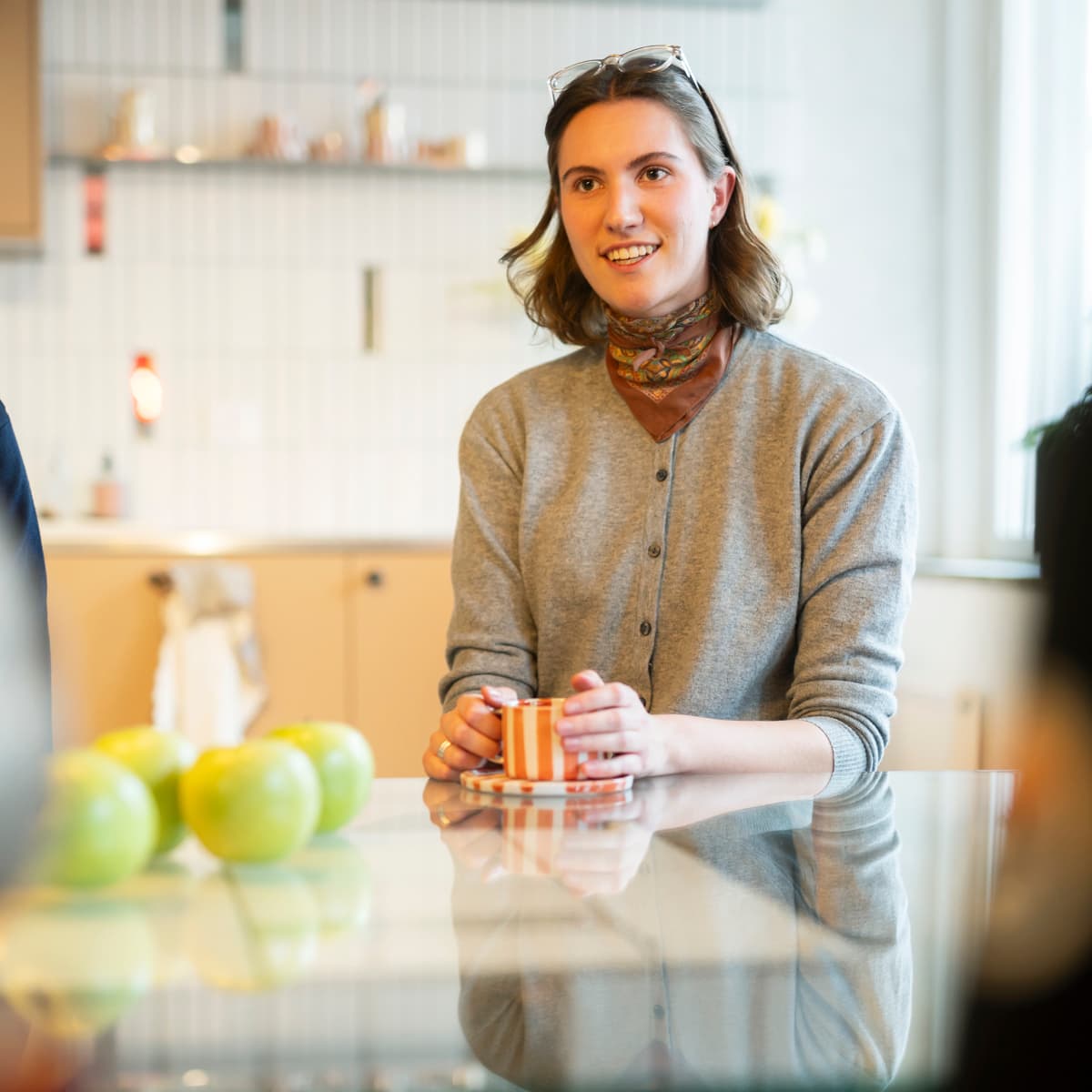 En kvinna sitter vid ett köksbord med glasskiva.