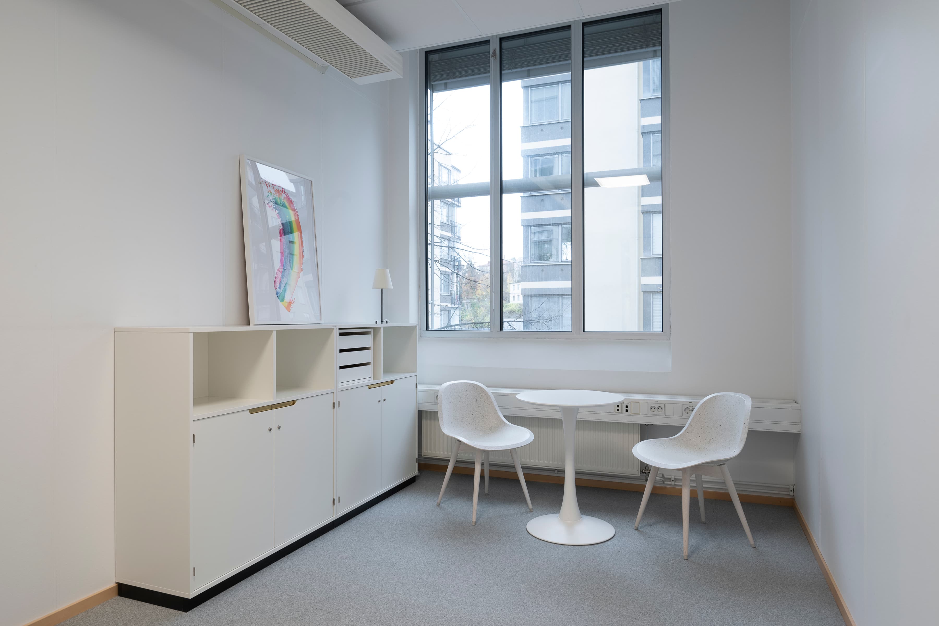 Ett mötesrum med ett fönster, bord och två stolar.