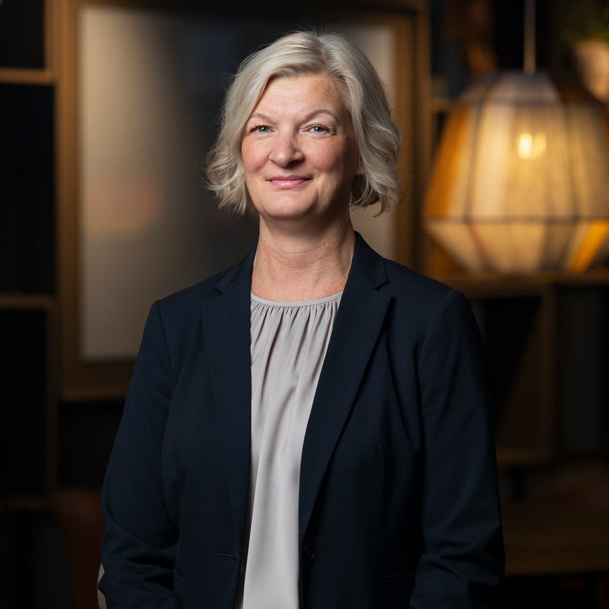 En kvinna i svart jacka står i ett rum.