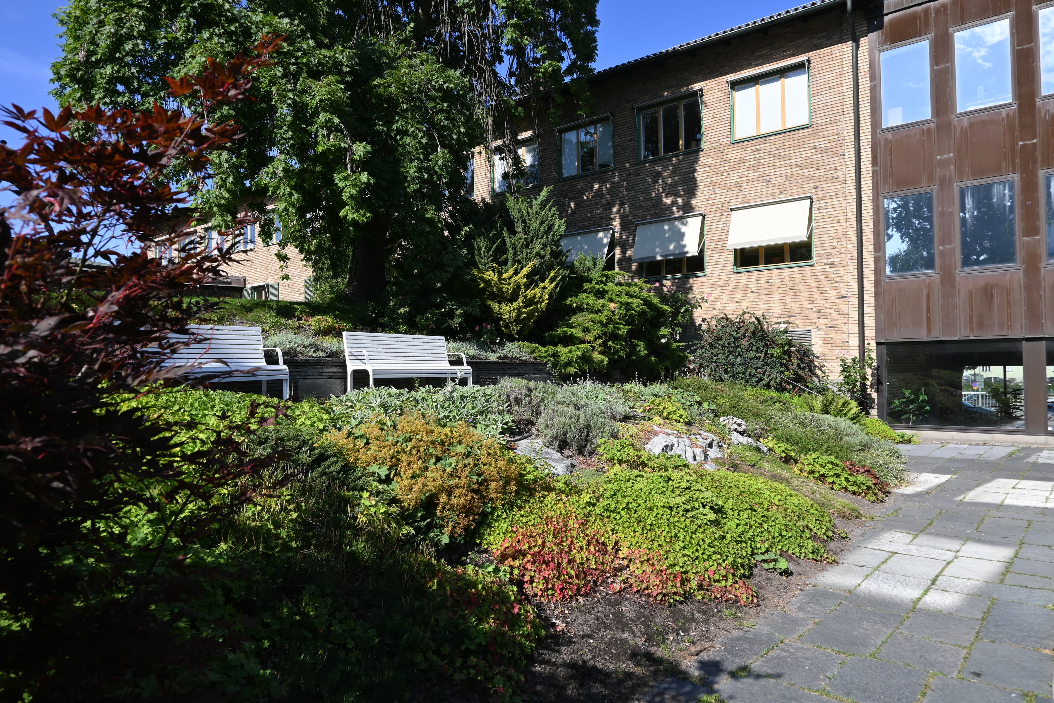 En tegelbyggnad med en trädgård framför.