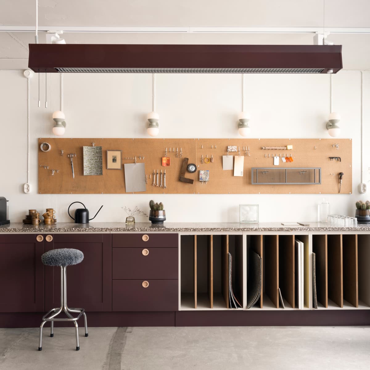 En köksdel med bänk, skåp och pall.