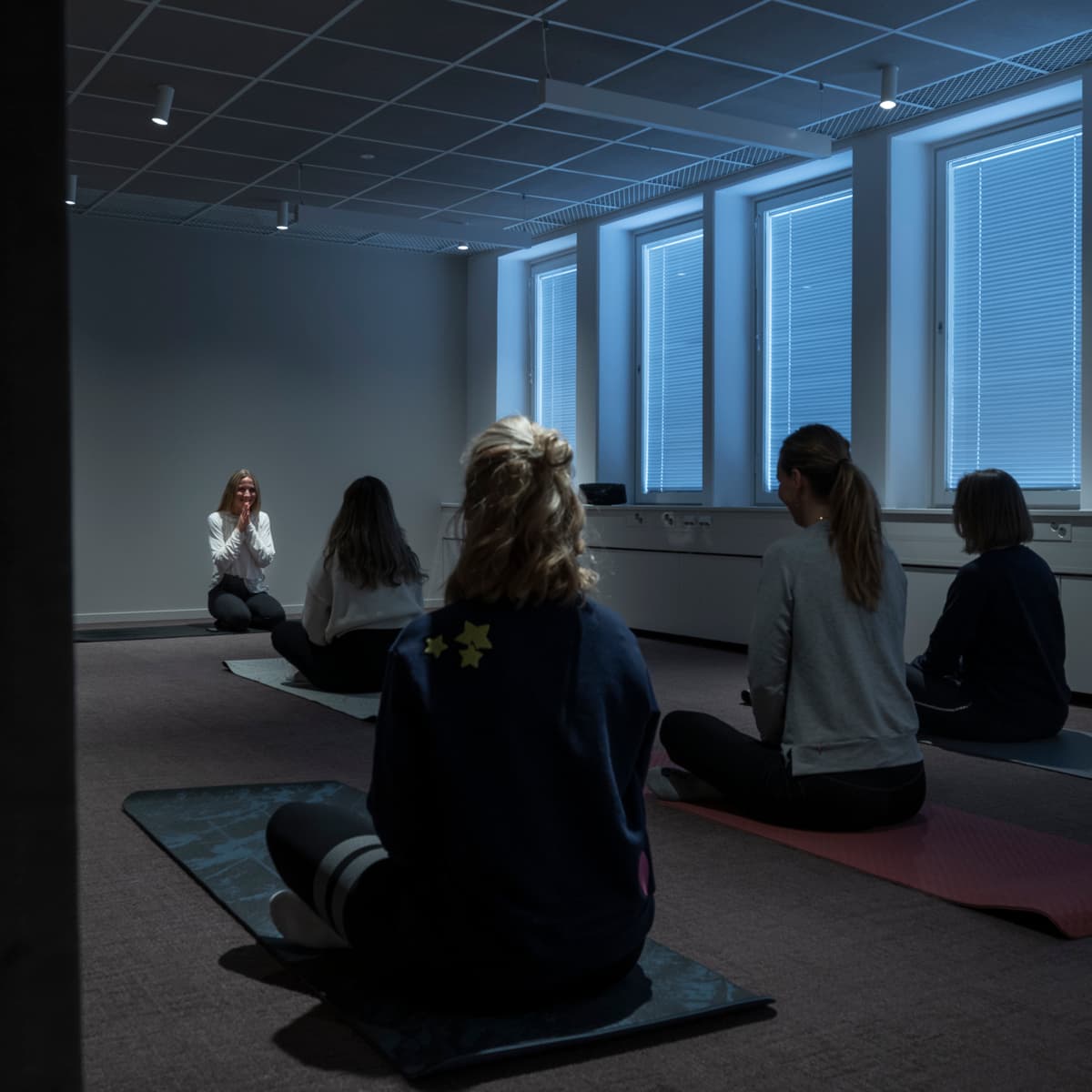 En grupp människor som sitter på yogamattor i ett rum.
