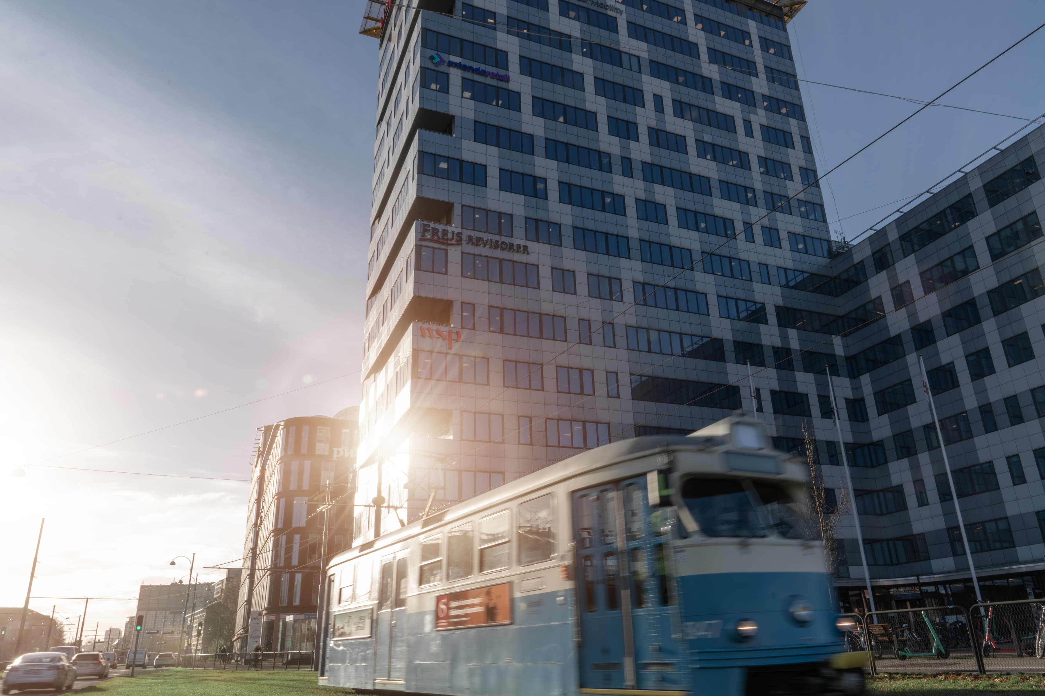 Ett blått och vitt tåg som passerar en hög byggnad.