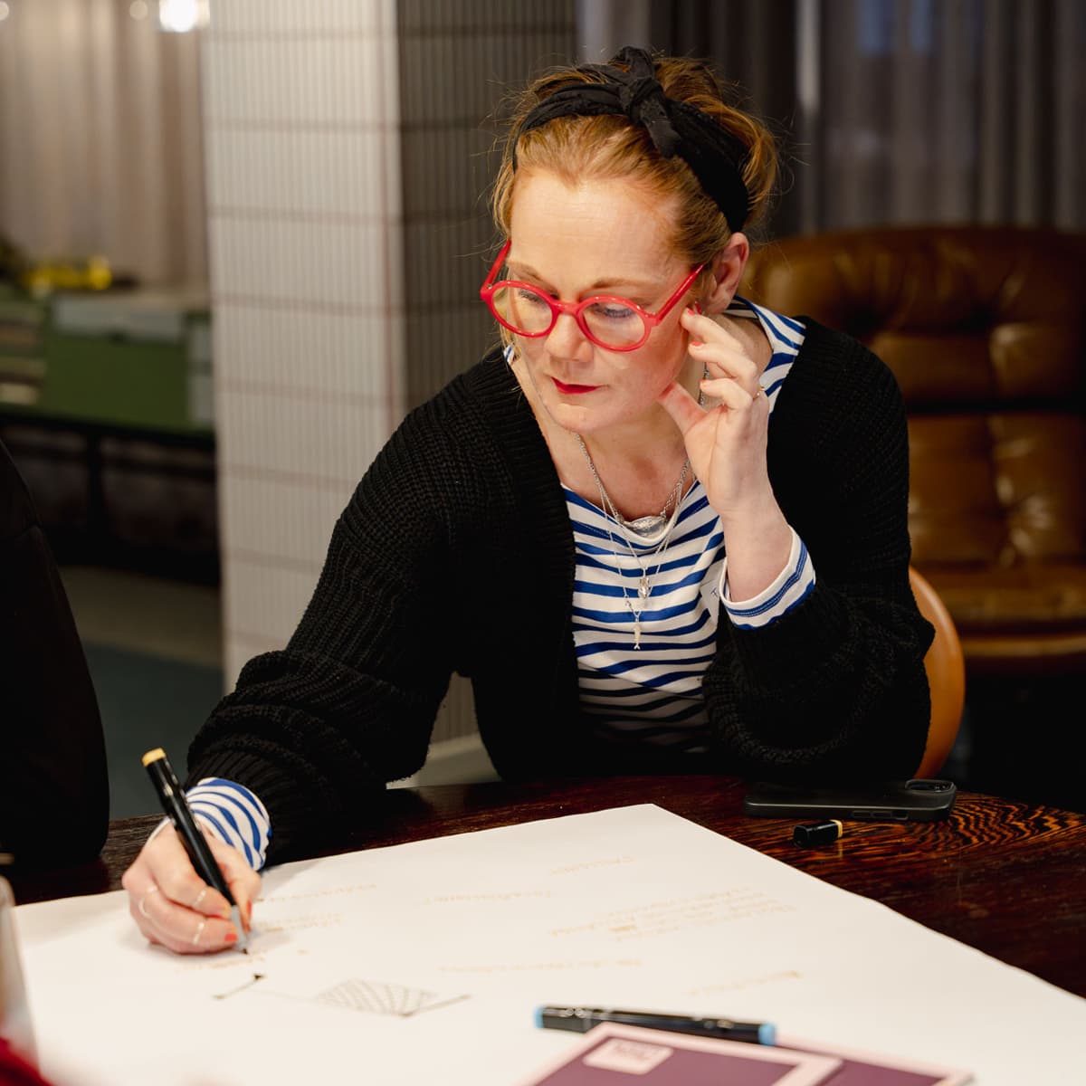 En kvinna sitter vid ett bord och skriver på ett papper.
