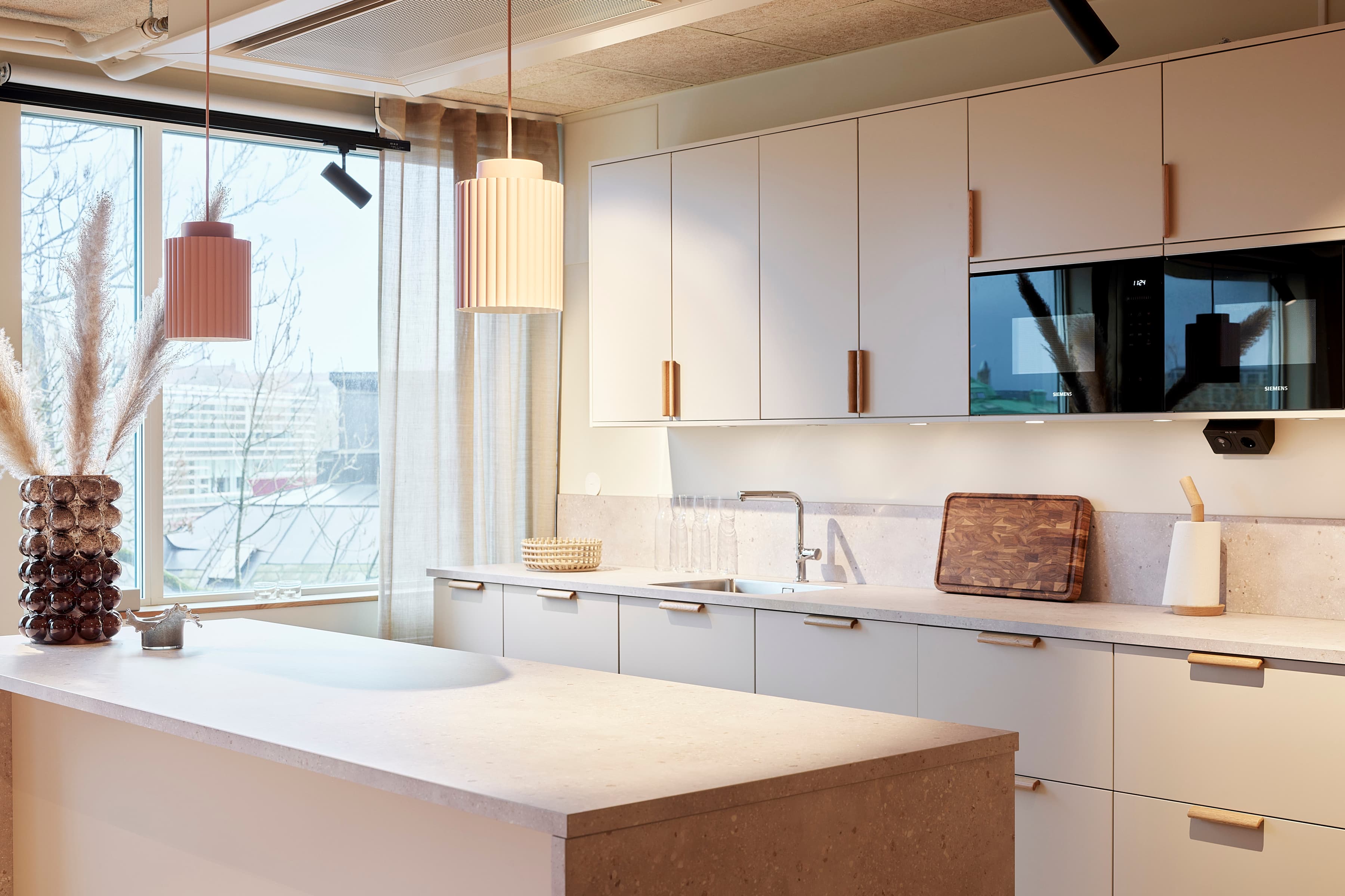 Ett kök med ett stort fönster och en vit bänkskiva.