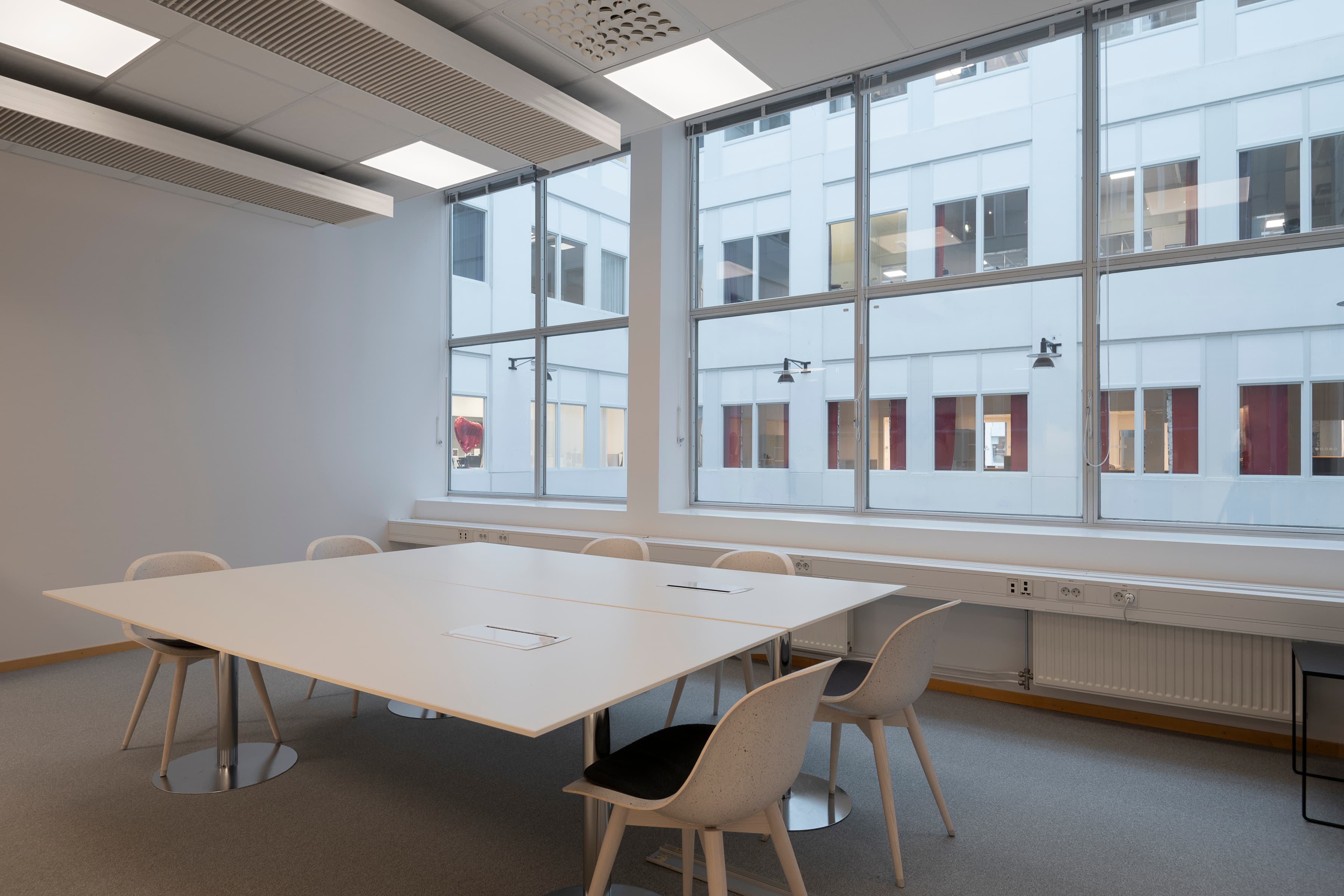 Ett bord och stolar i ett rum med stora fönster.