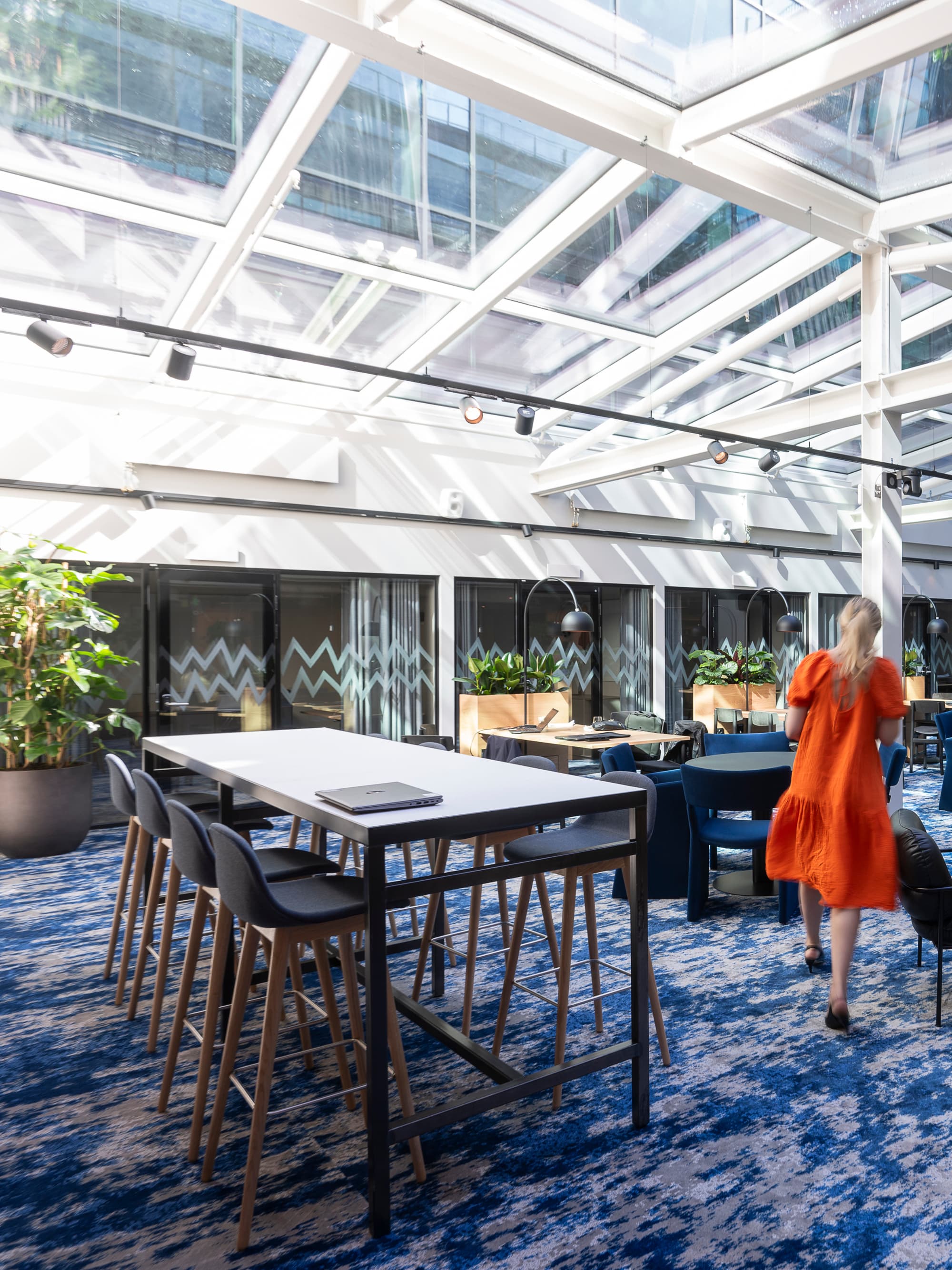 En kvinna i en orange klänning står i ett stort rum.