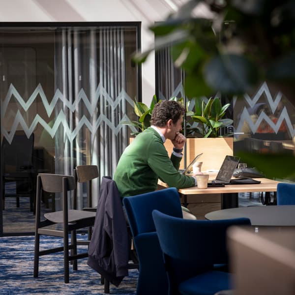 En man sitter vid ett bord och använder en bärbar dator.