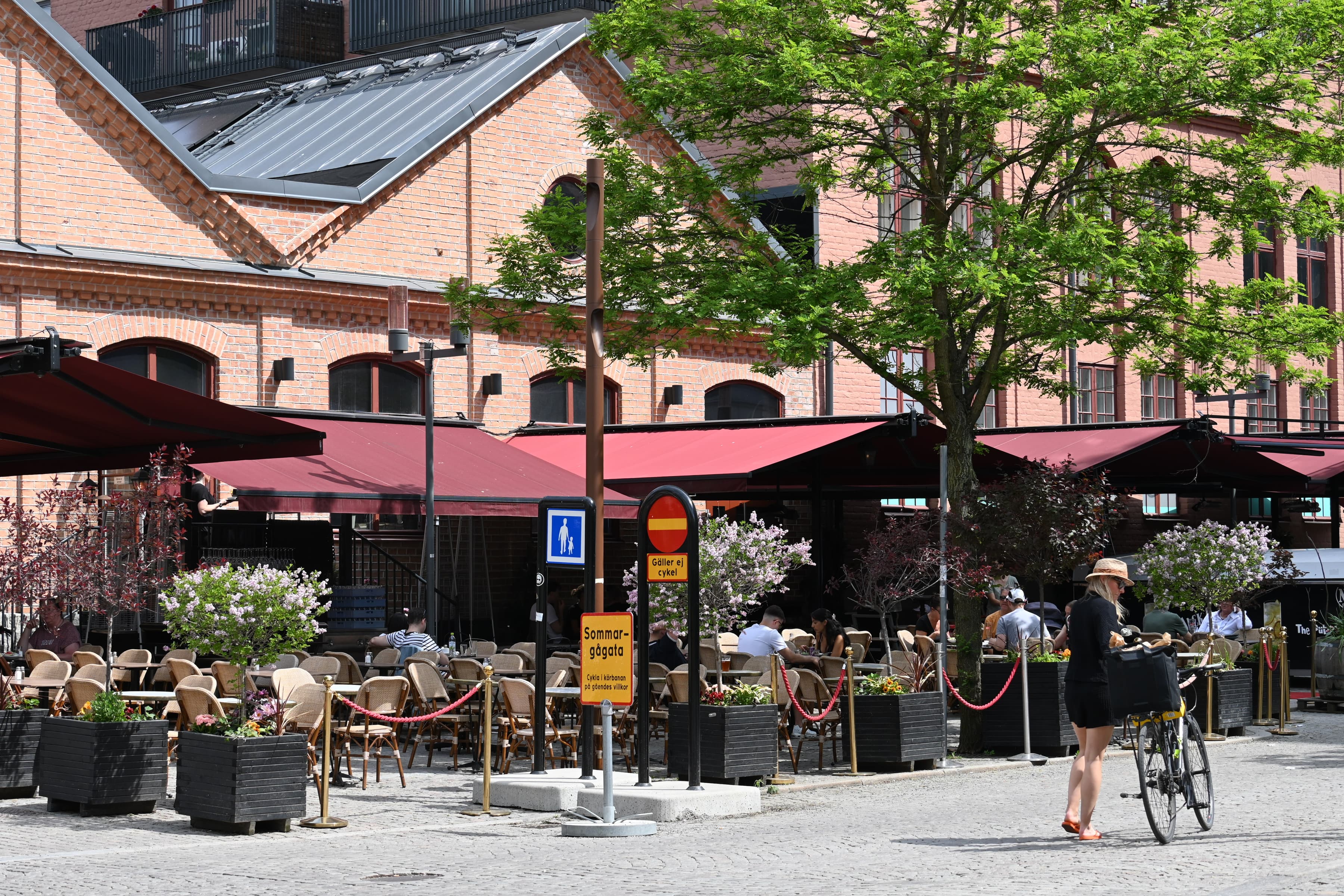 En kvinna går längs en gata bredvid en hög byggnad.