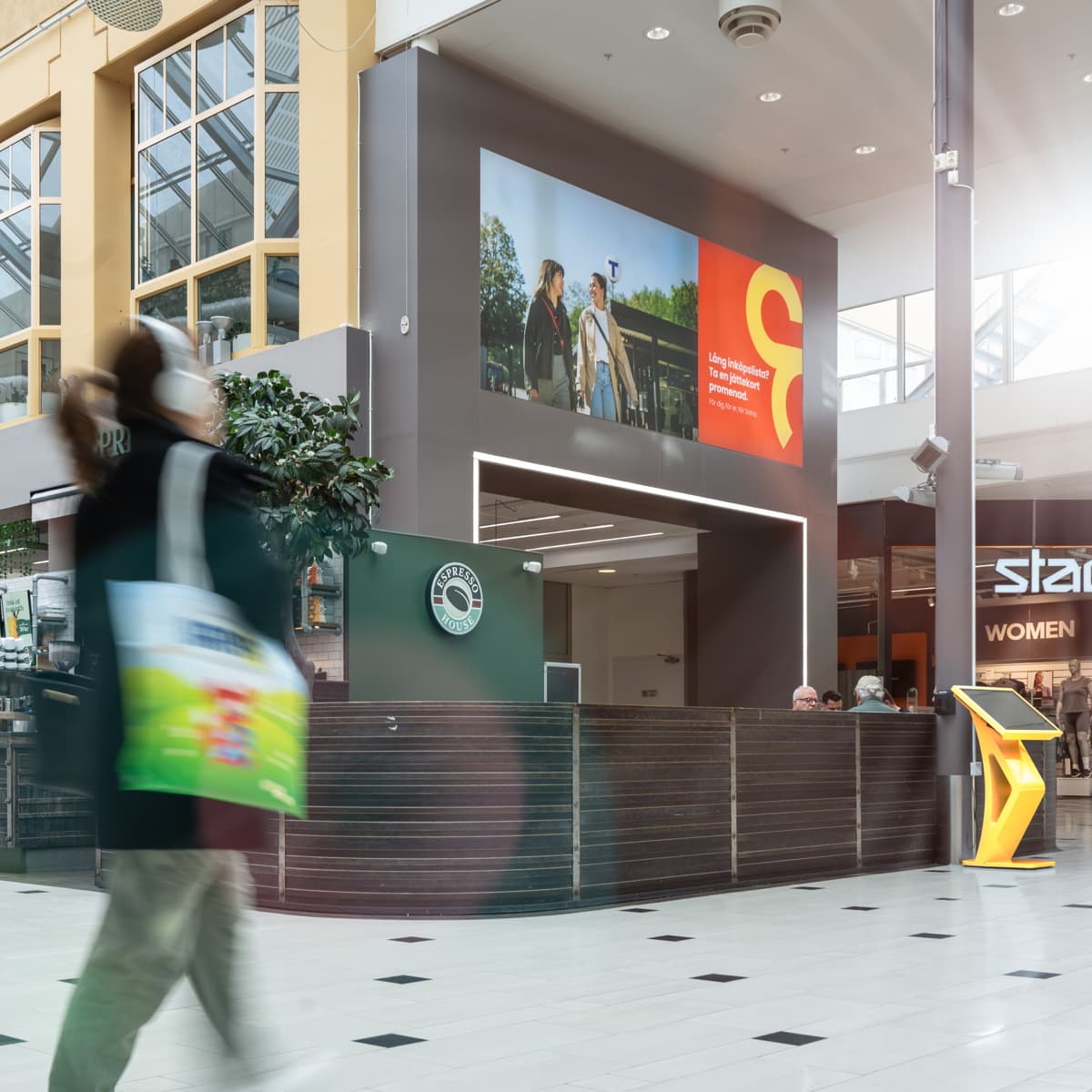 Ett suddigt foto av människor som går i ett köpcentrum.