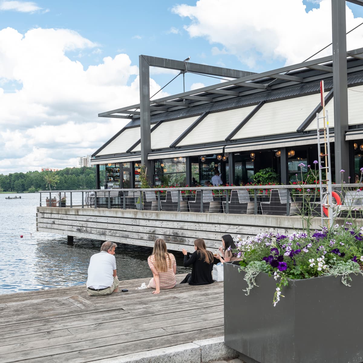 En grupp människor som sitter på en brygga intill ett vattendrag.