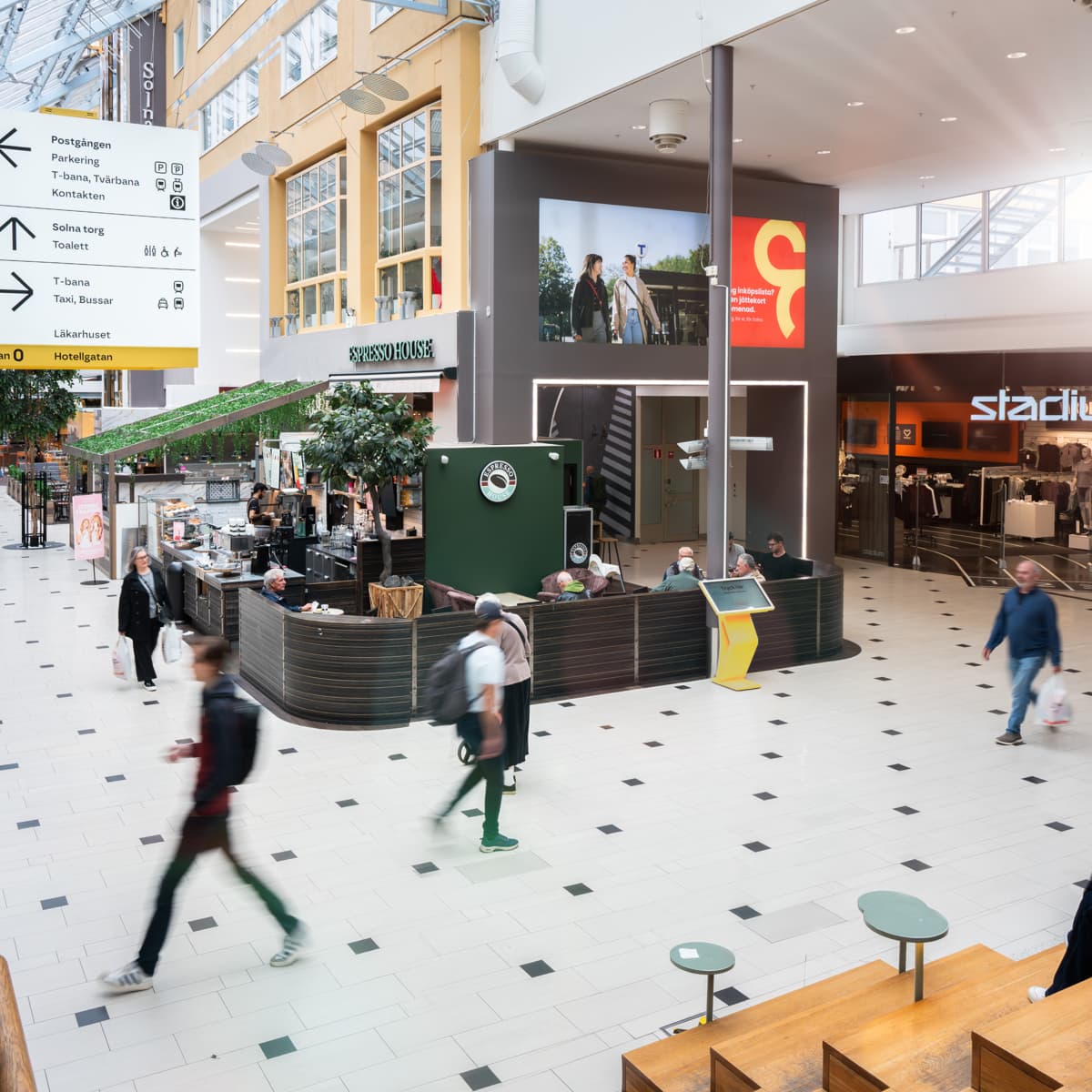 En grupp människor som går runt i en galleria.