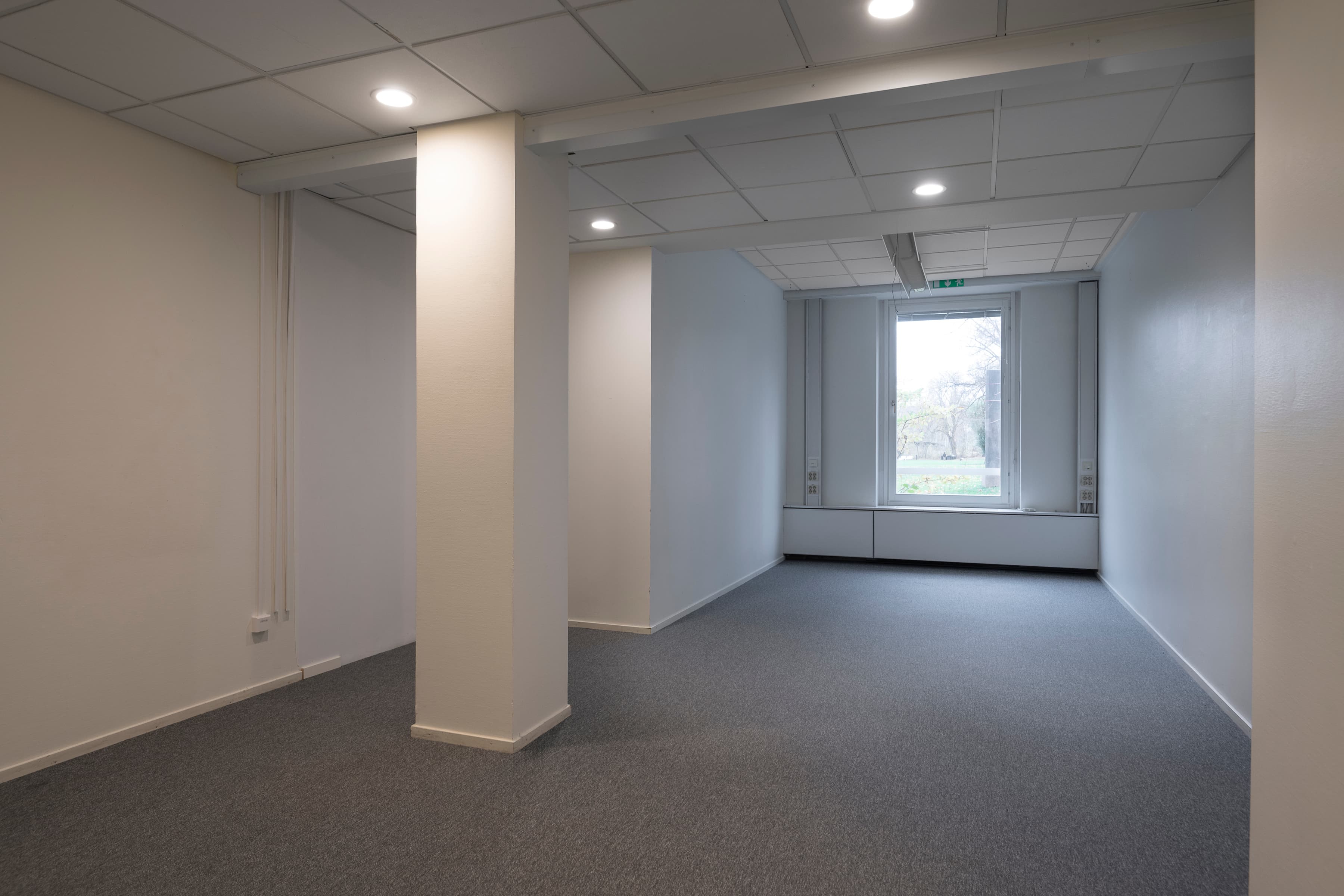 Ett tomt rum med en vit vägg och ett fönster.