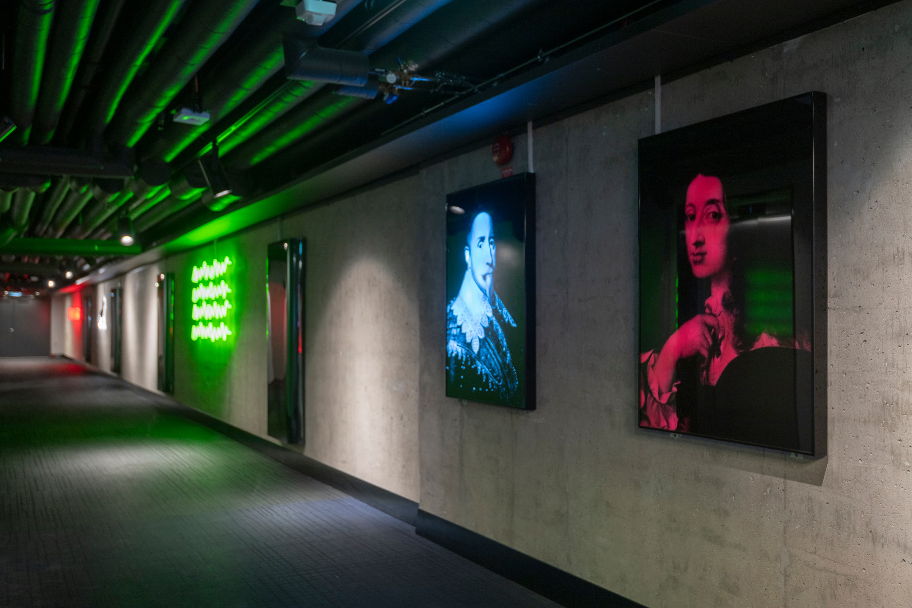 En lång korridor med affischer på väggen.