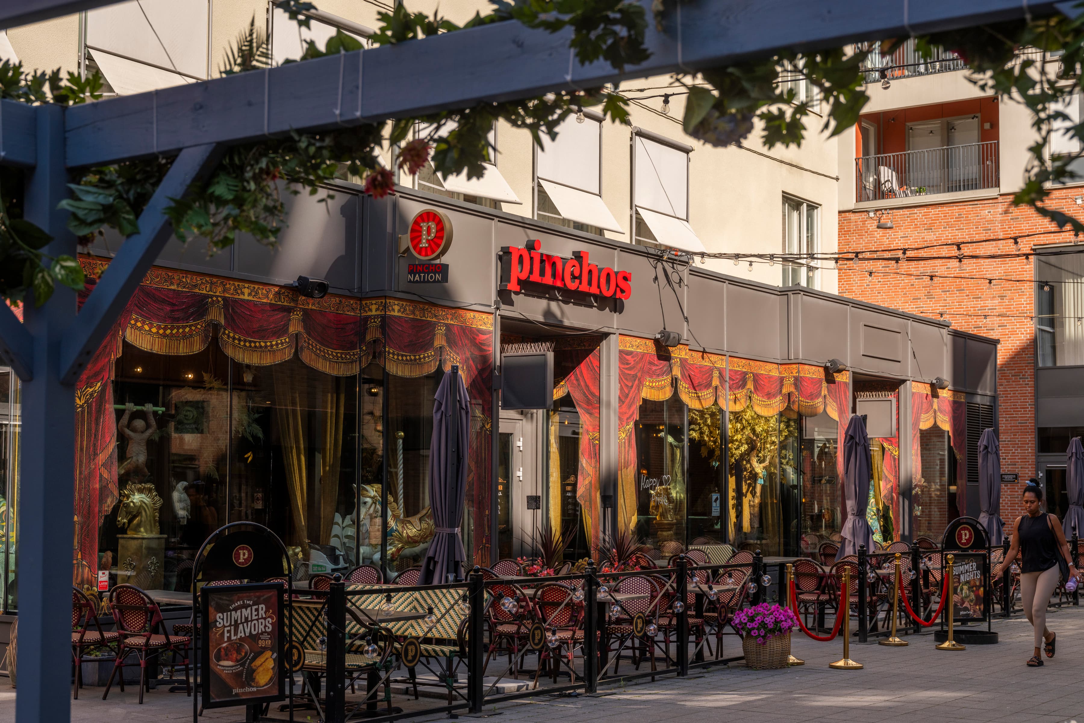 En grupp människor som går längs trottoaren bredvid en restaurang.