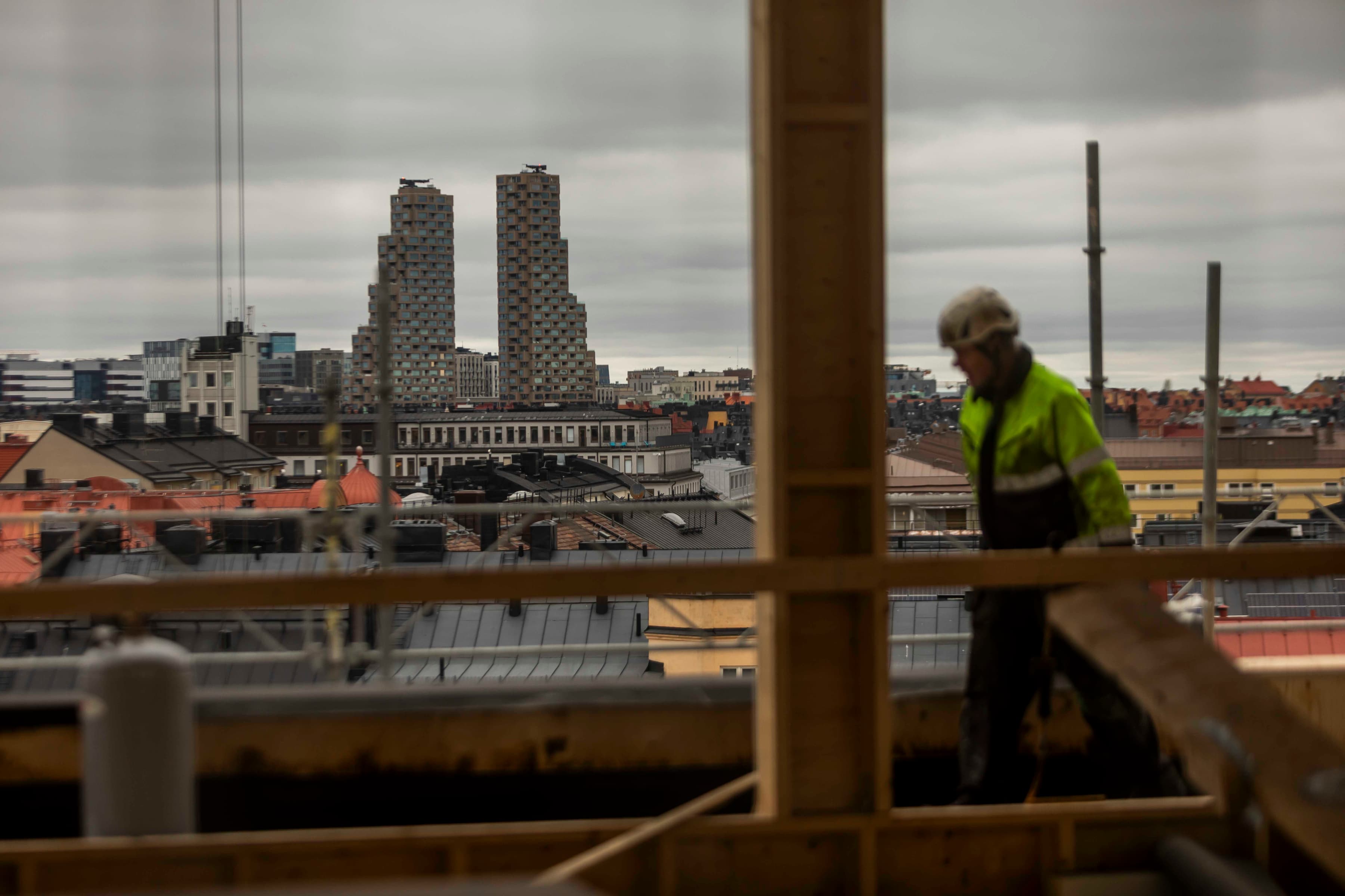 En man står på ett tak bredvid en hög byggnad.