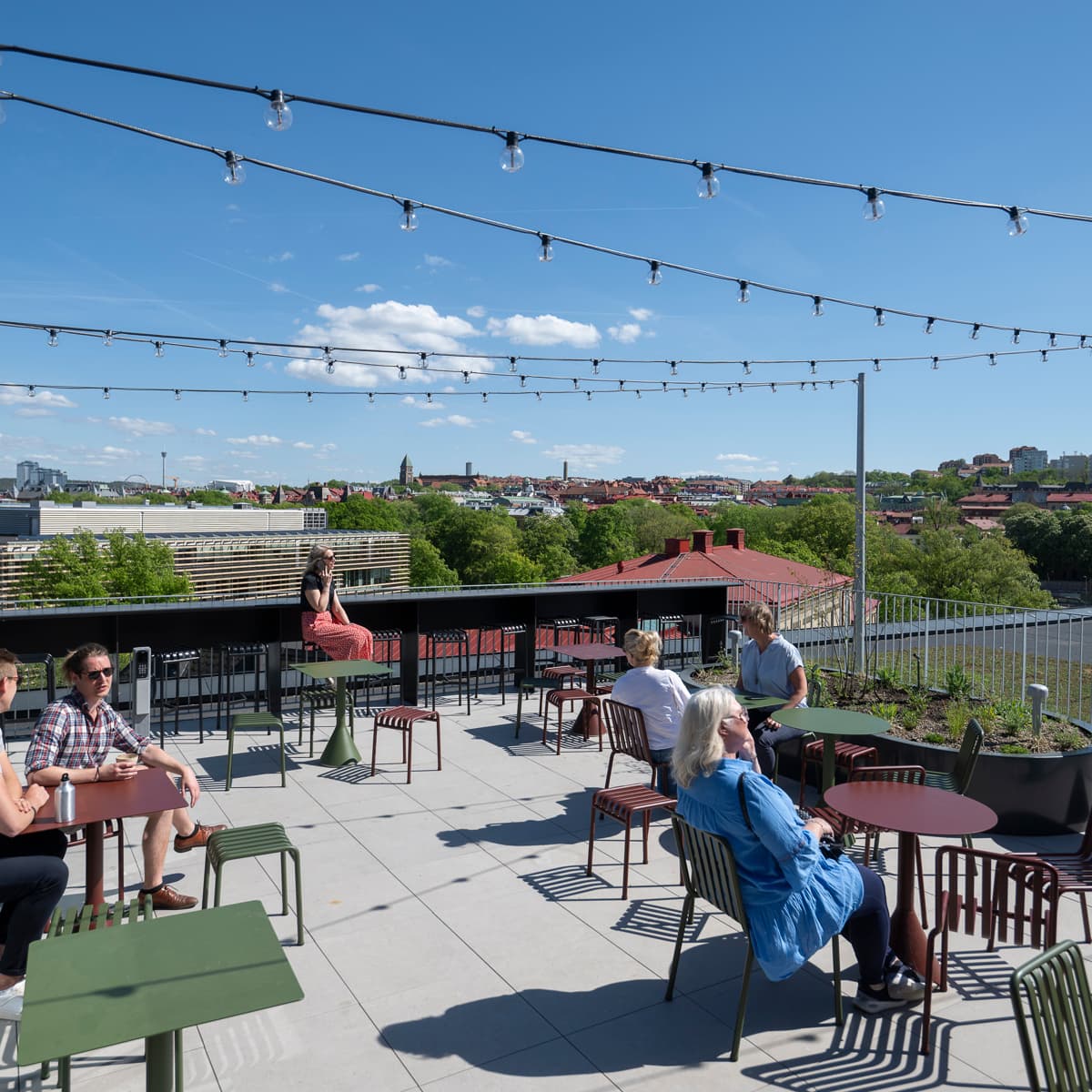 En grupp människor som sitter vid bord på toppen av ett tak.