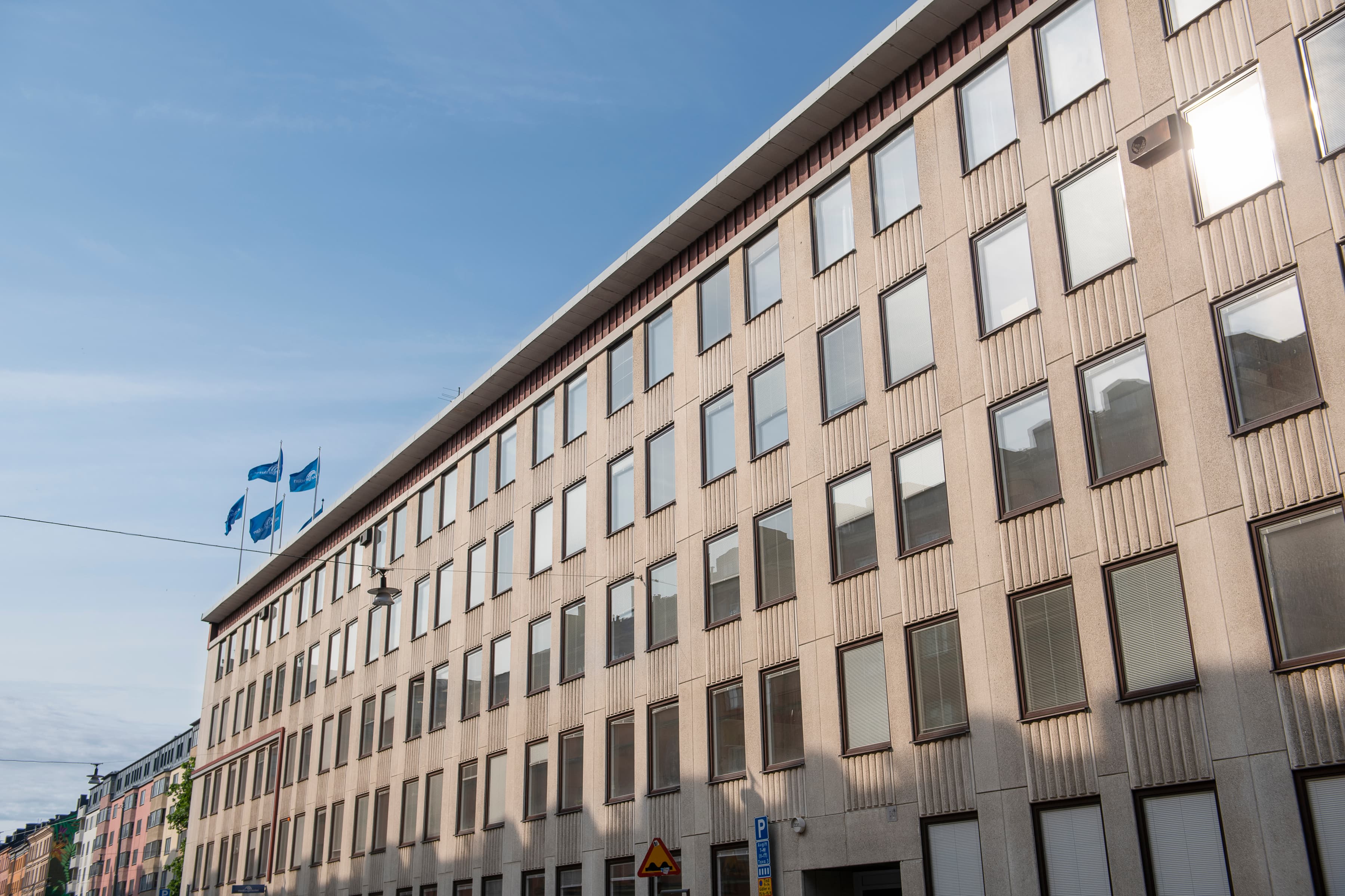 En hög byggnad med många fönster intill en gata.