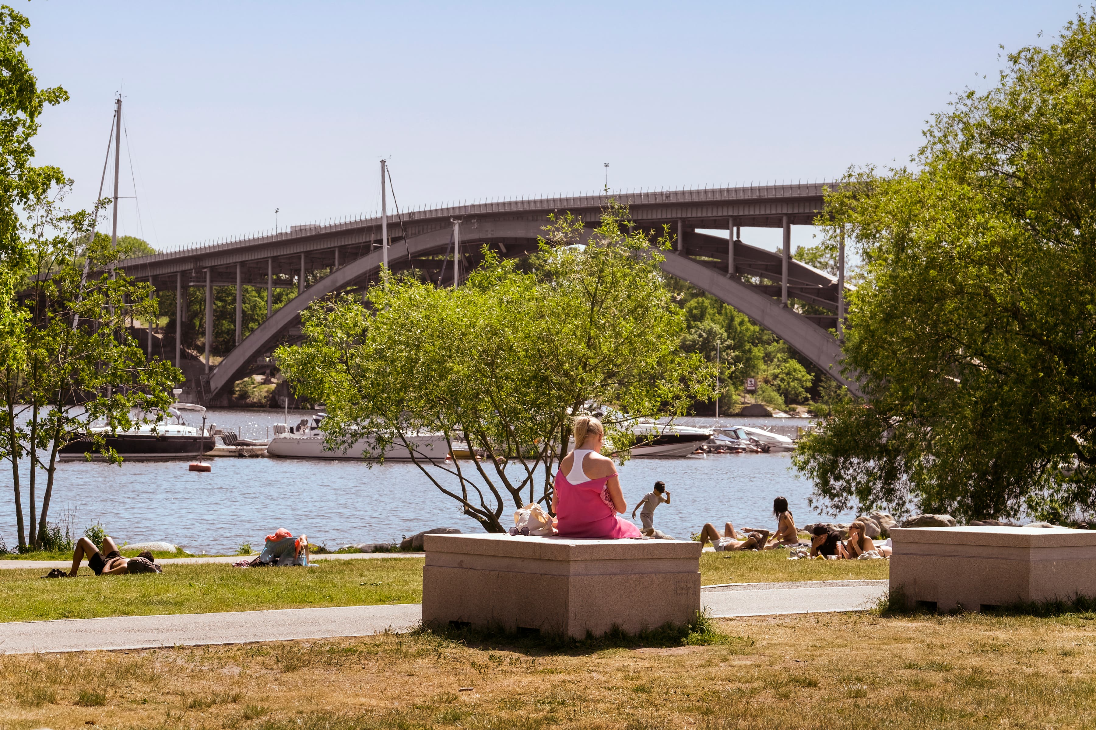 En kvinna sitter på en bänk framför en flod.