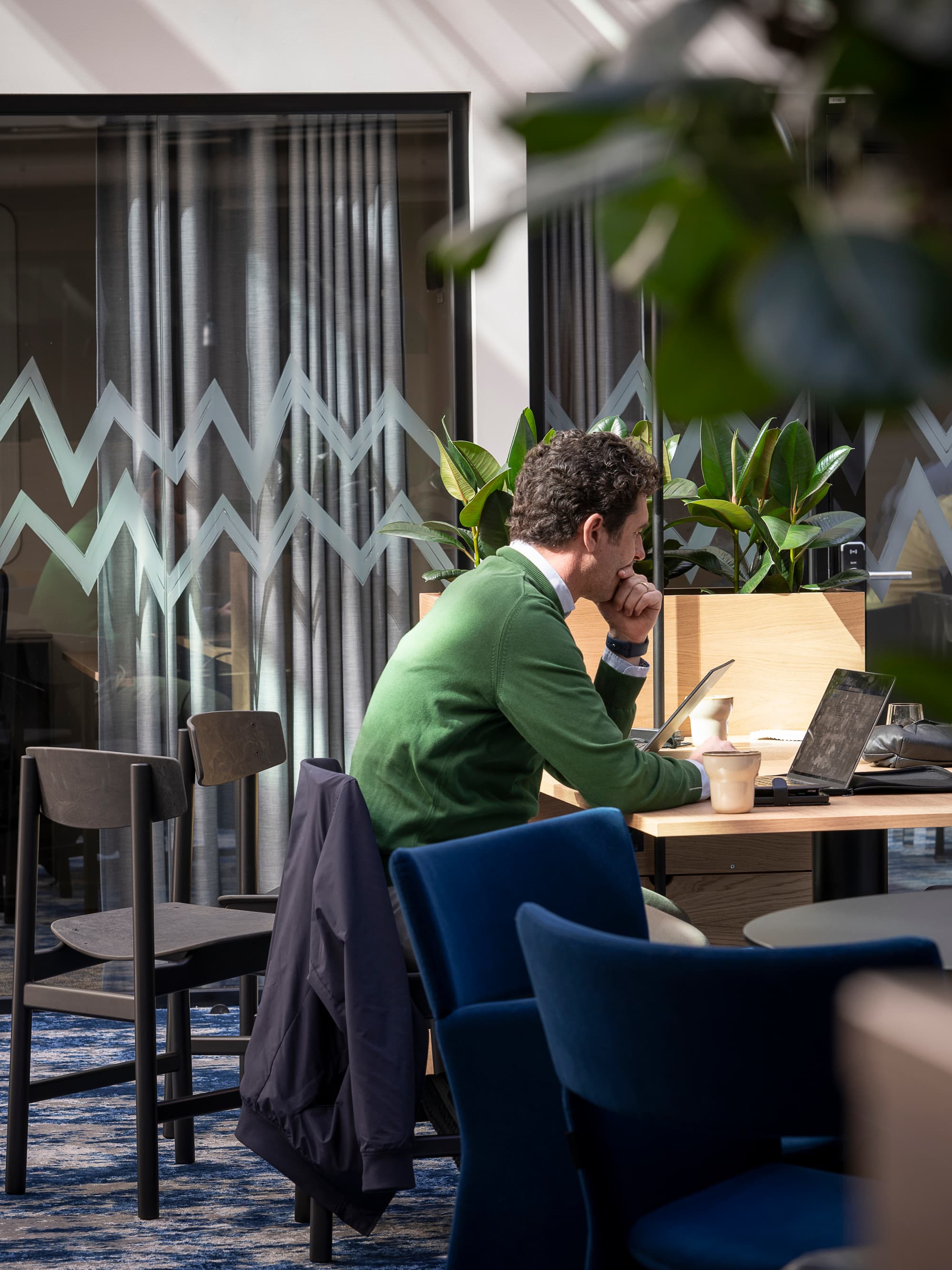 En man sitter vid ett bord och använder en bärbar dator.