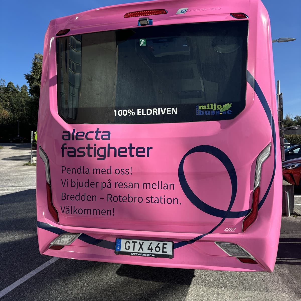 En rosa buss parkerad på en parkeringsplats.