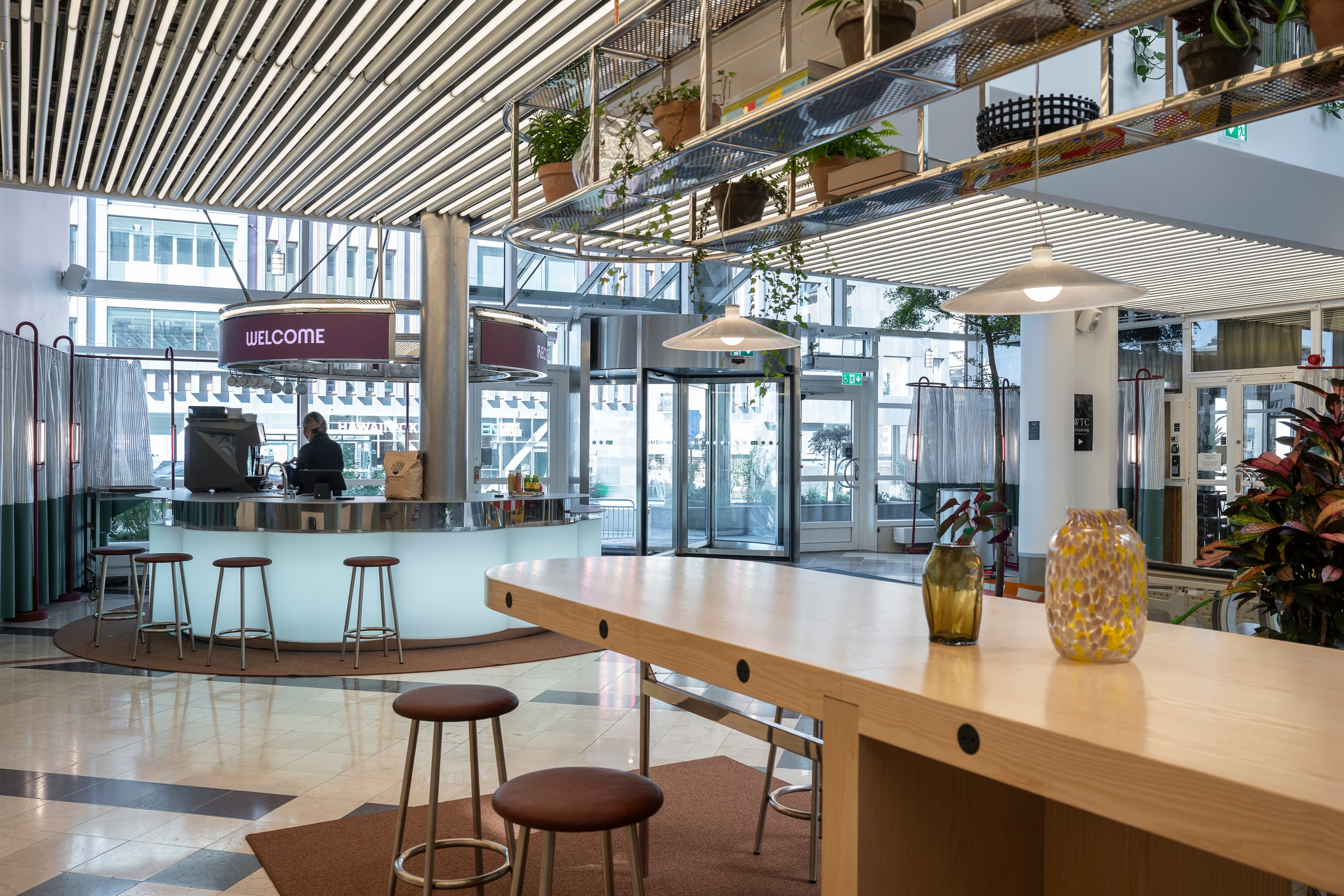 Ett rum med en bänk, pallar och växter i det.