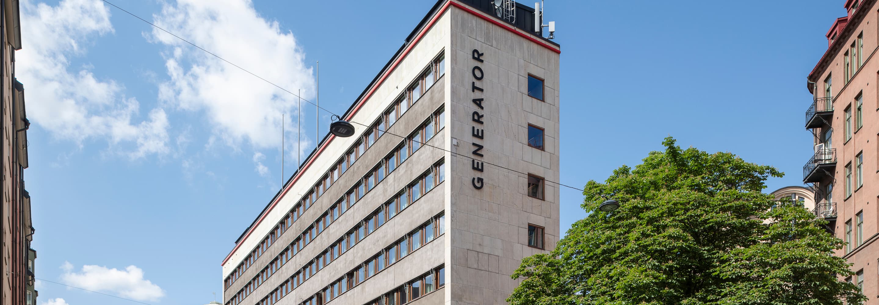 En stadsgata kantad av parkerade bilar och höga byggnader.