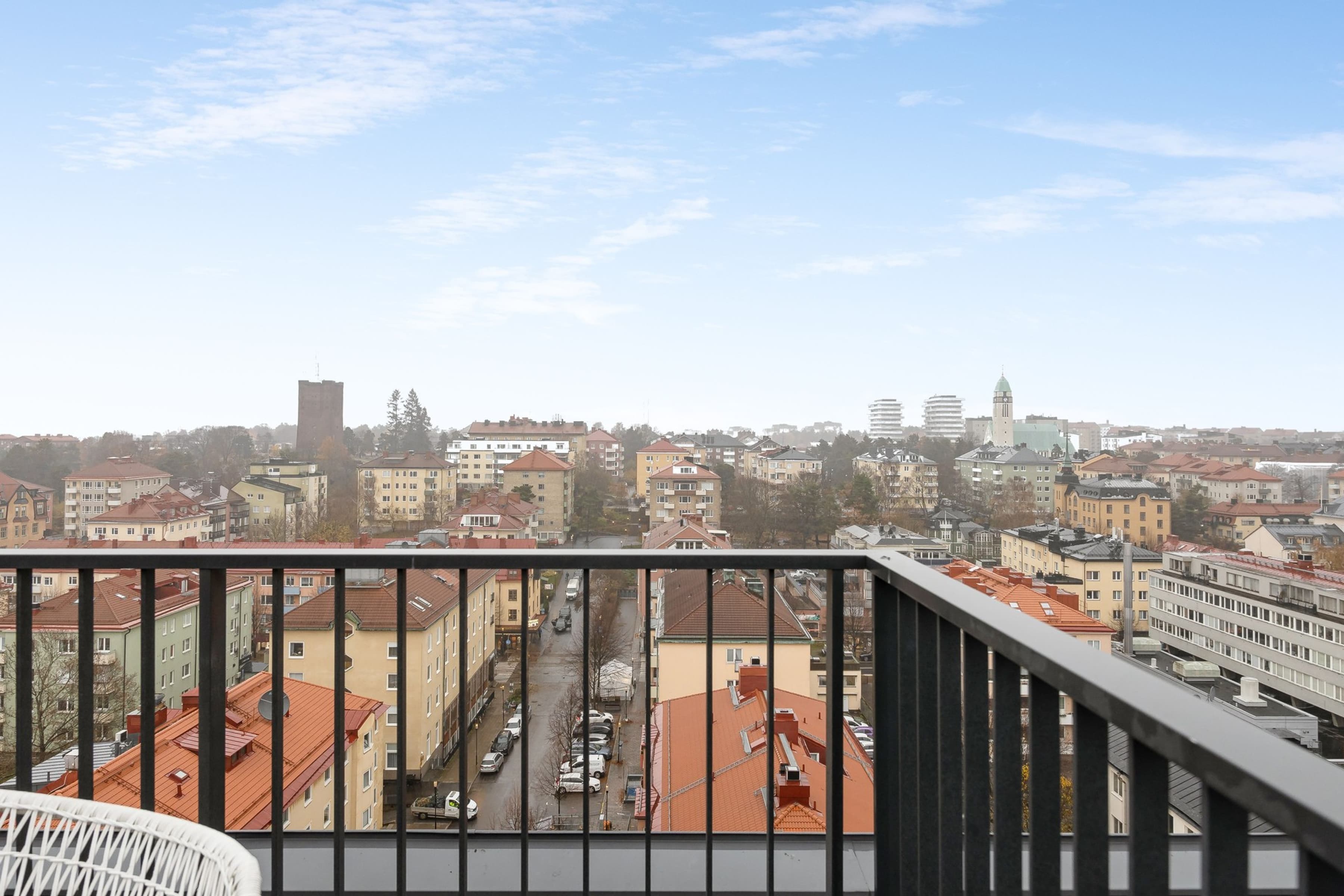 En balkong med en stol och utsikt över en stad.