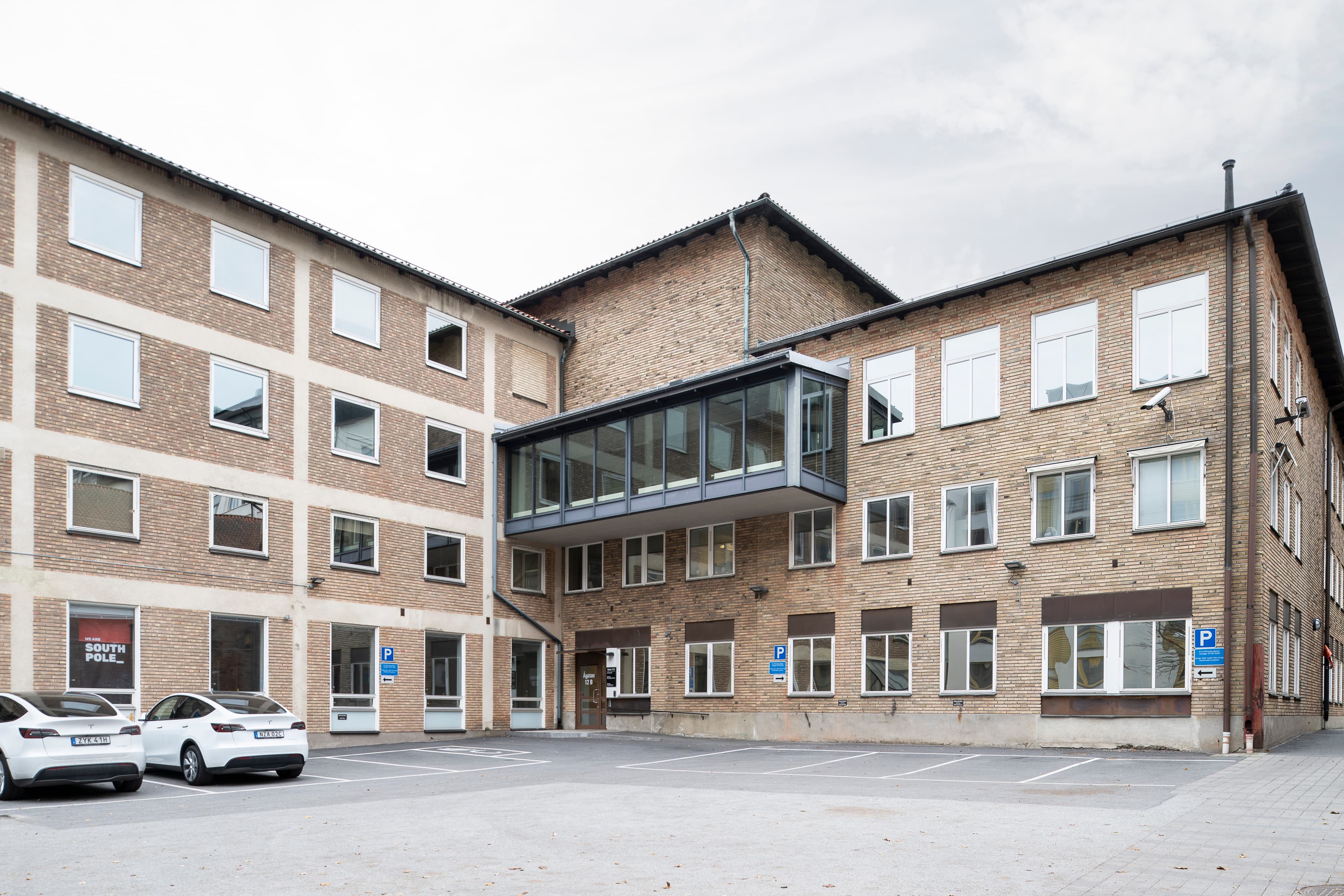 En parkeringsplats framför en byggnad med bilar parkerade framför den.