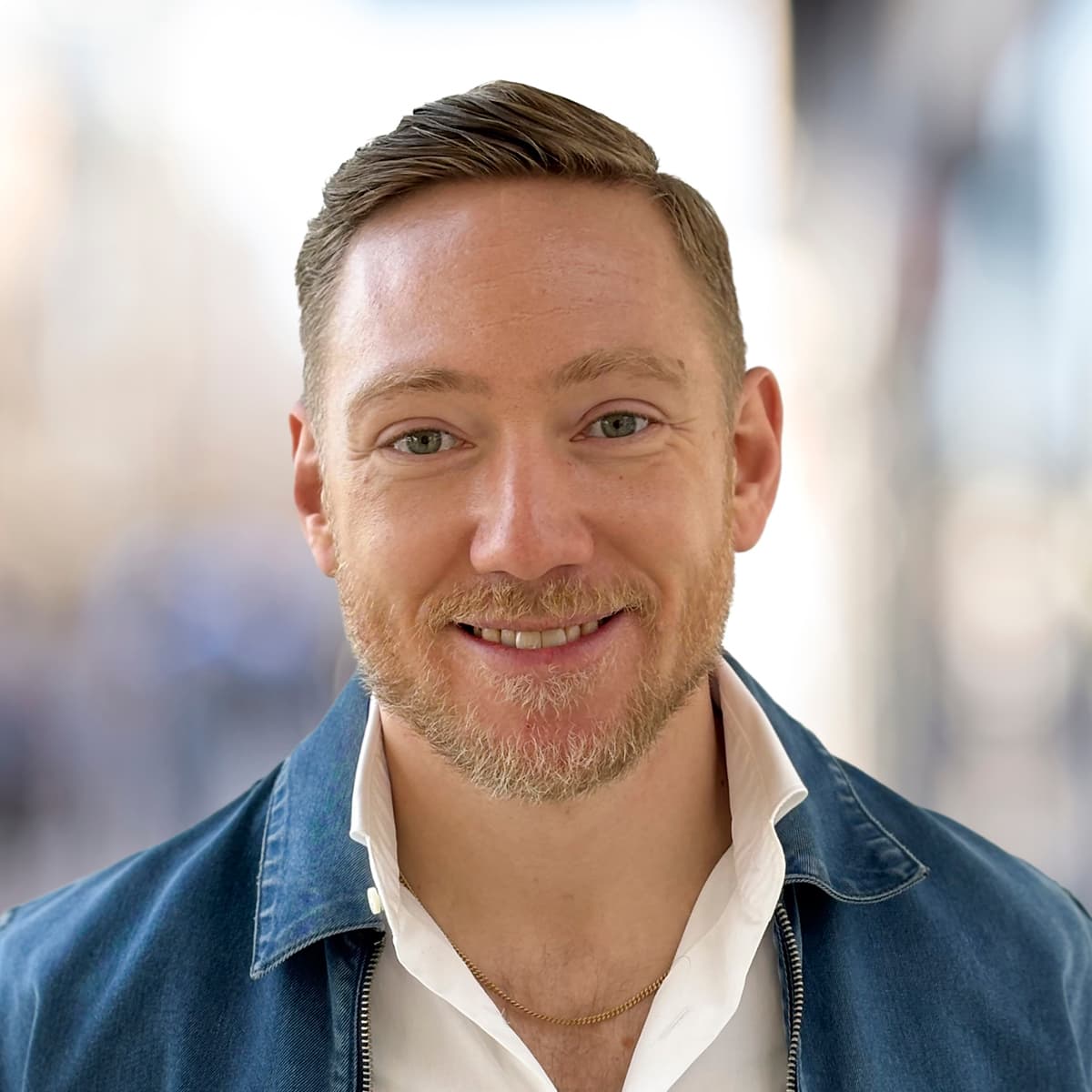 En man i jeansjacka ler mot kameran.