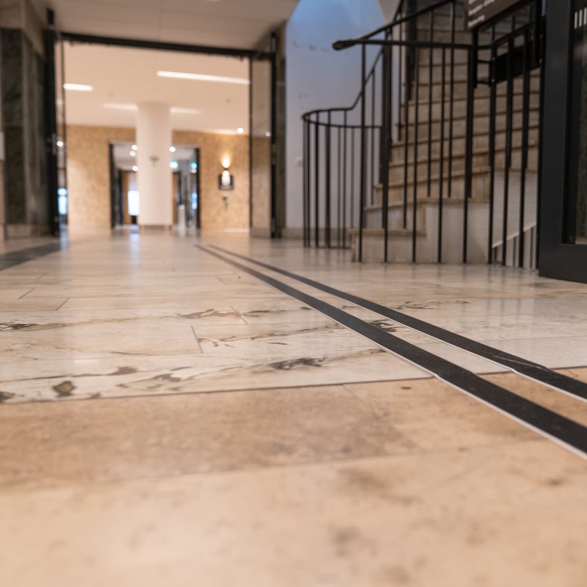 En hall med marmorgolv och en svart dörr.