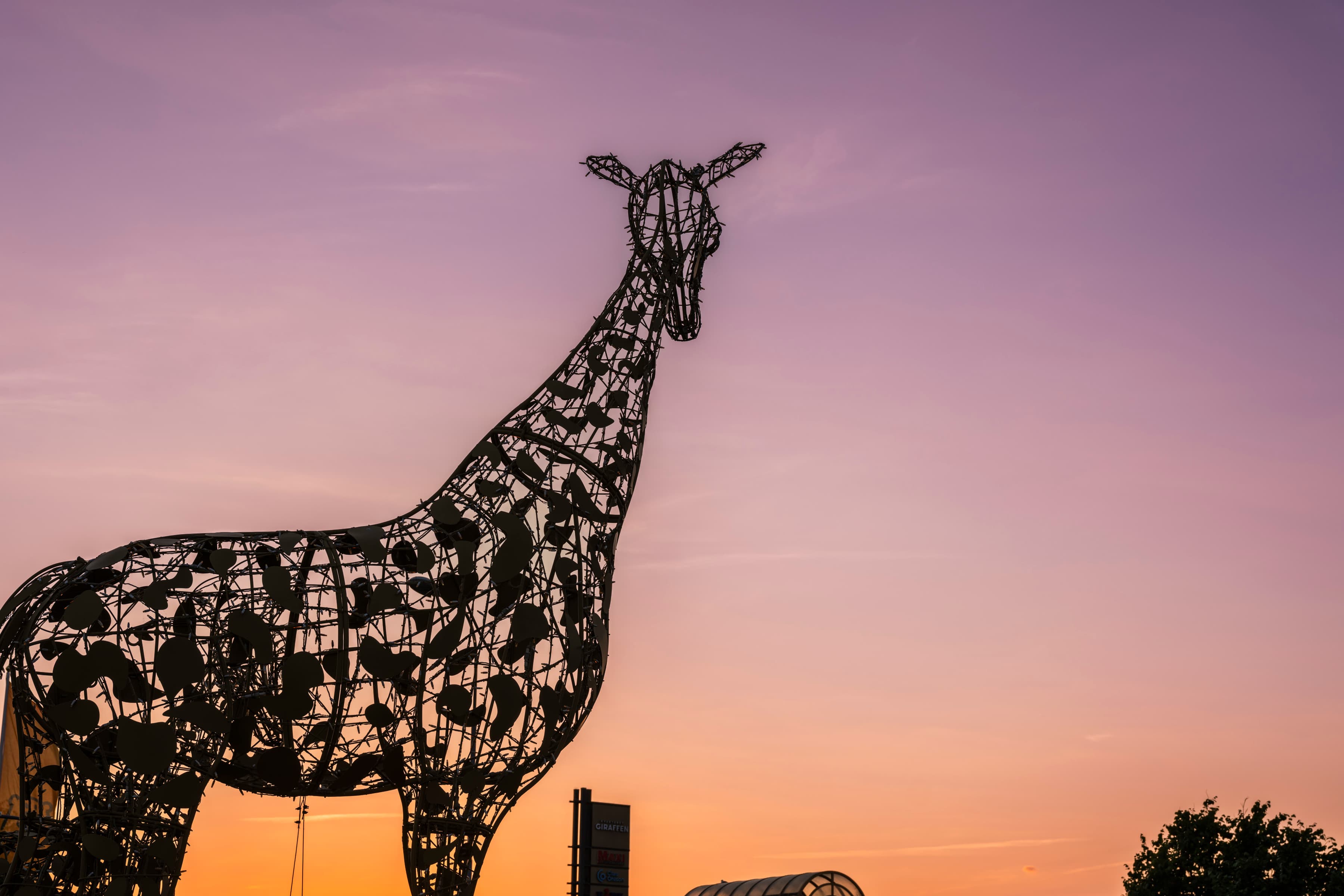 En staty av en giraff framför en solnedgång.